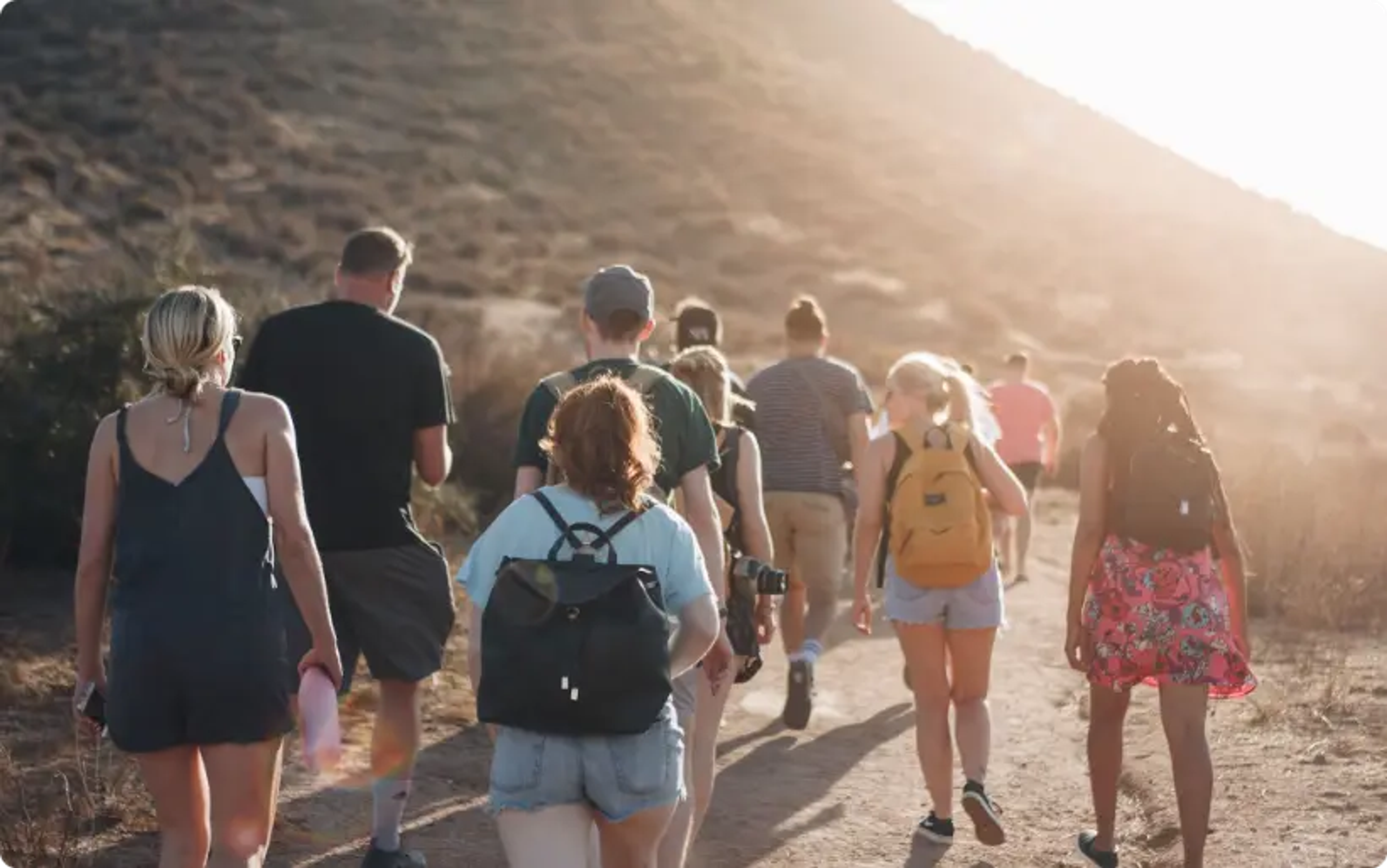mensen die over een onverharde weg lopen nabij een berg tijdens de dag, meerdaagse tour