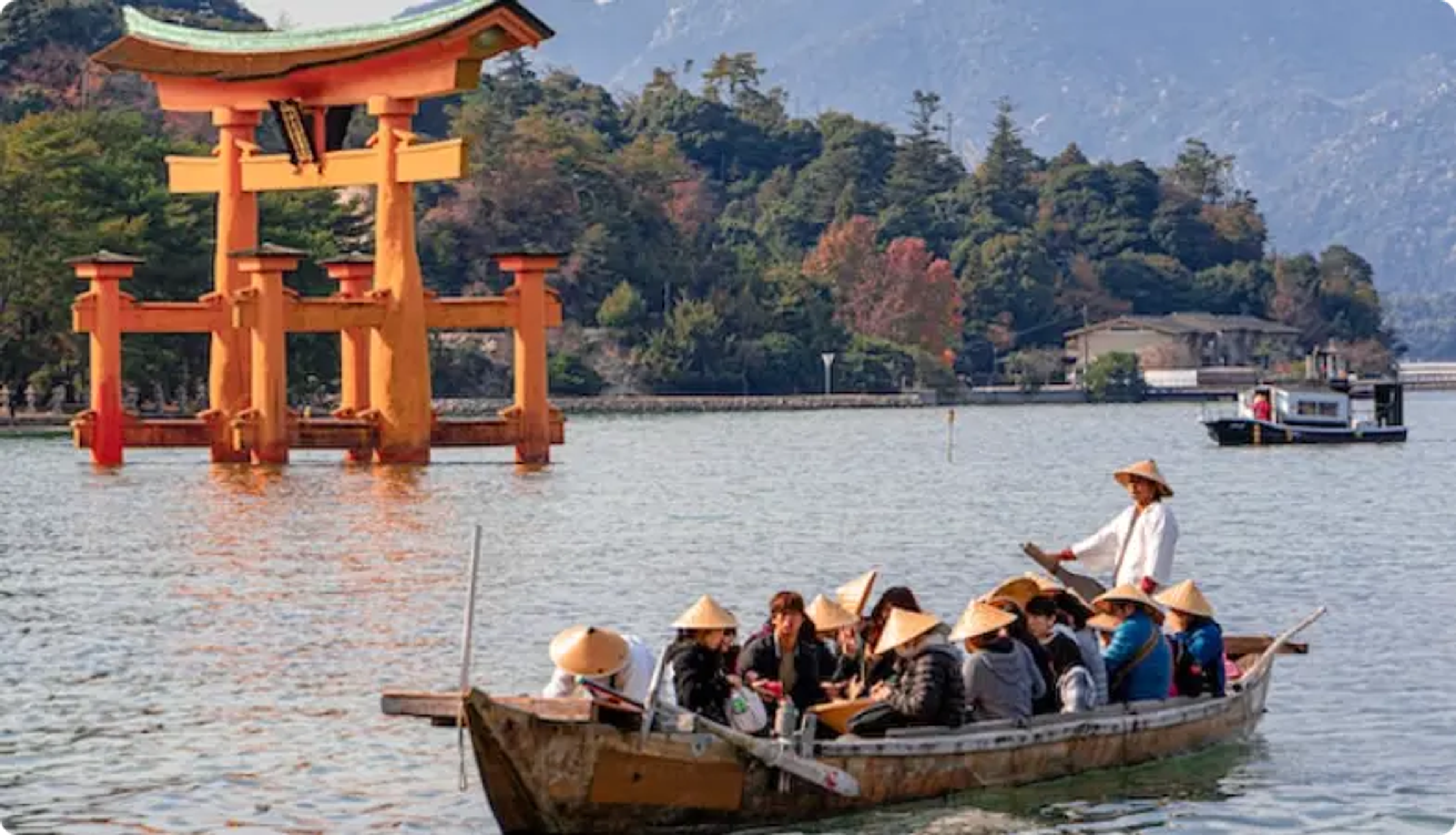Torii orange dans l'eau avec un bateau de touristes près de l'île Miyajima, Japon