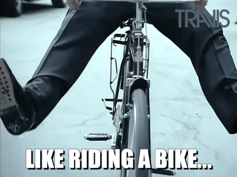 Primo piano di una bicicletta tra le gambe con il testo 'Come andare in bicicletta'