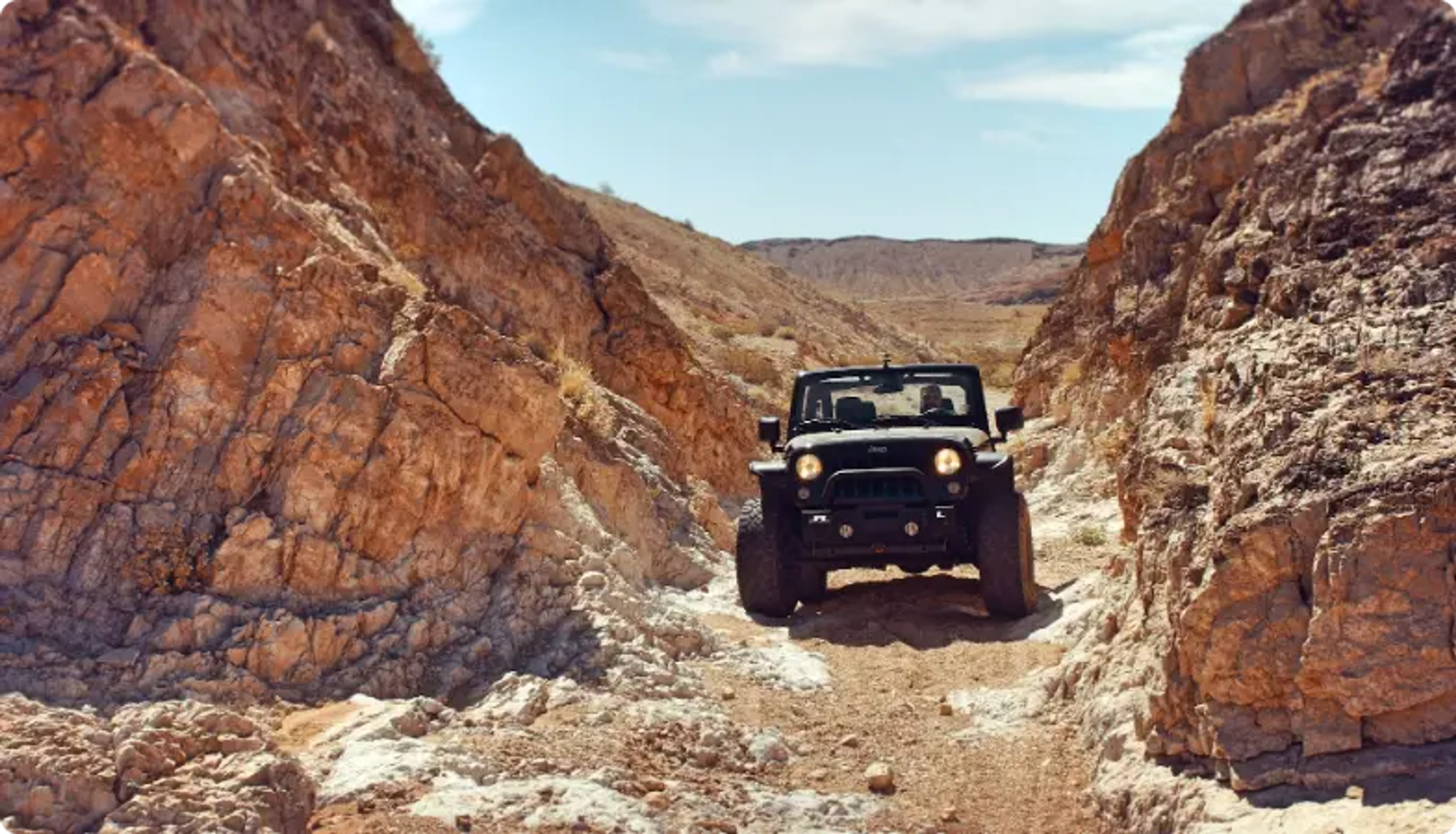 Jeep negro conduciendo a través de un cañón rocoso en un sendero de tierra accidentado