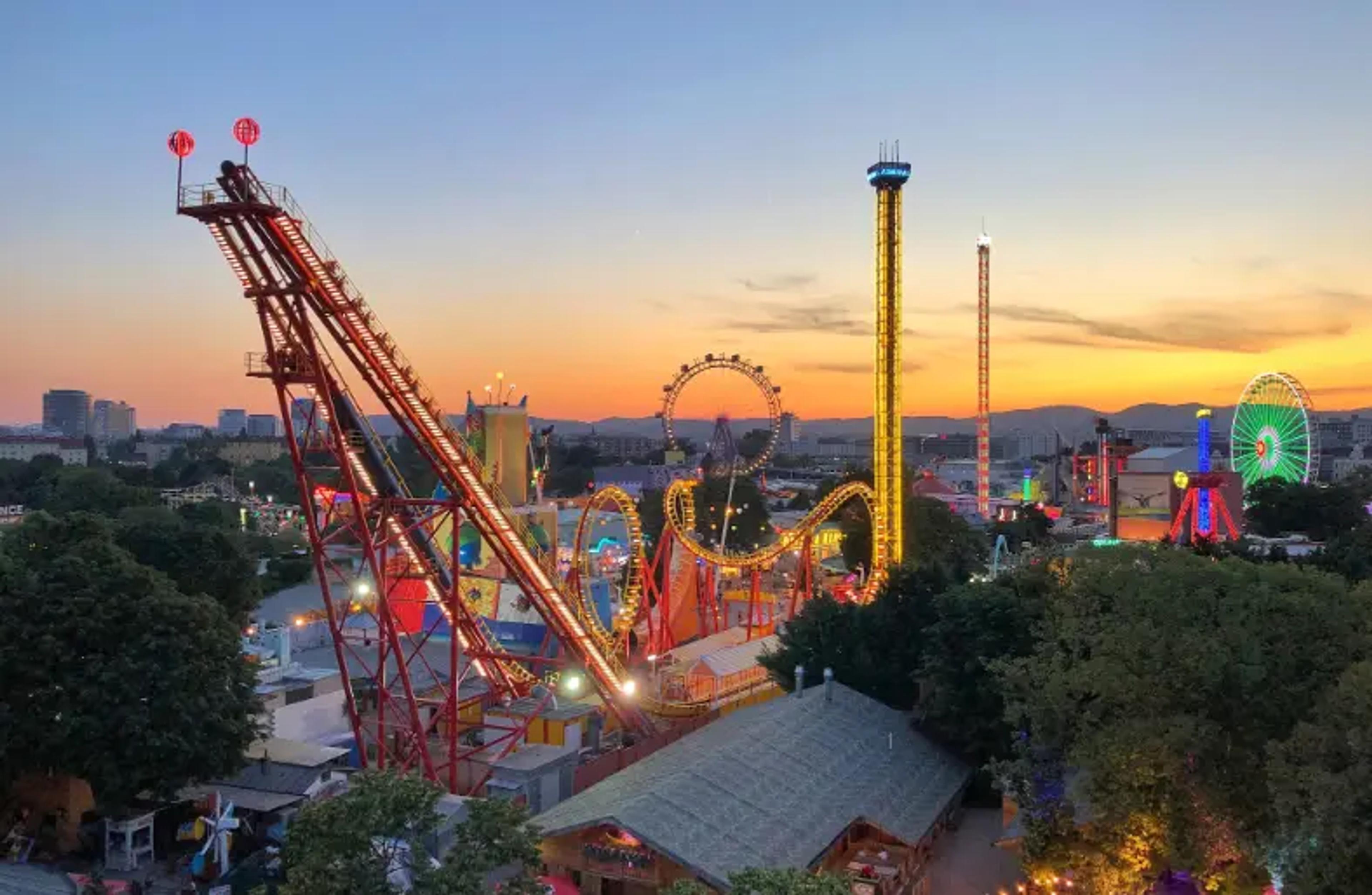Farverig forlystelsespark med rutsjebaner og pariserhjul ved solnedgang