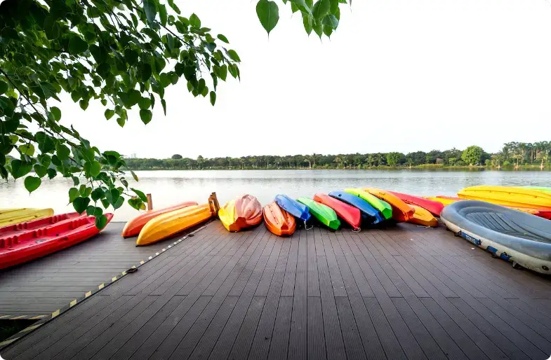 Kayaks colorés alignés sur un quai en bois près d'un lac verdoyant