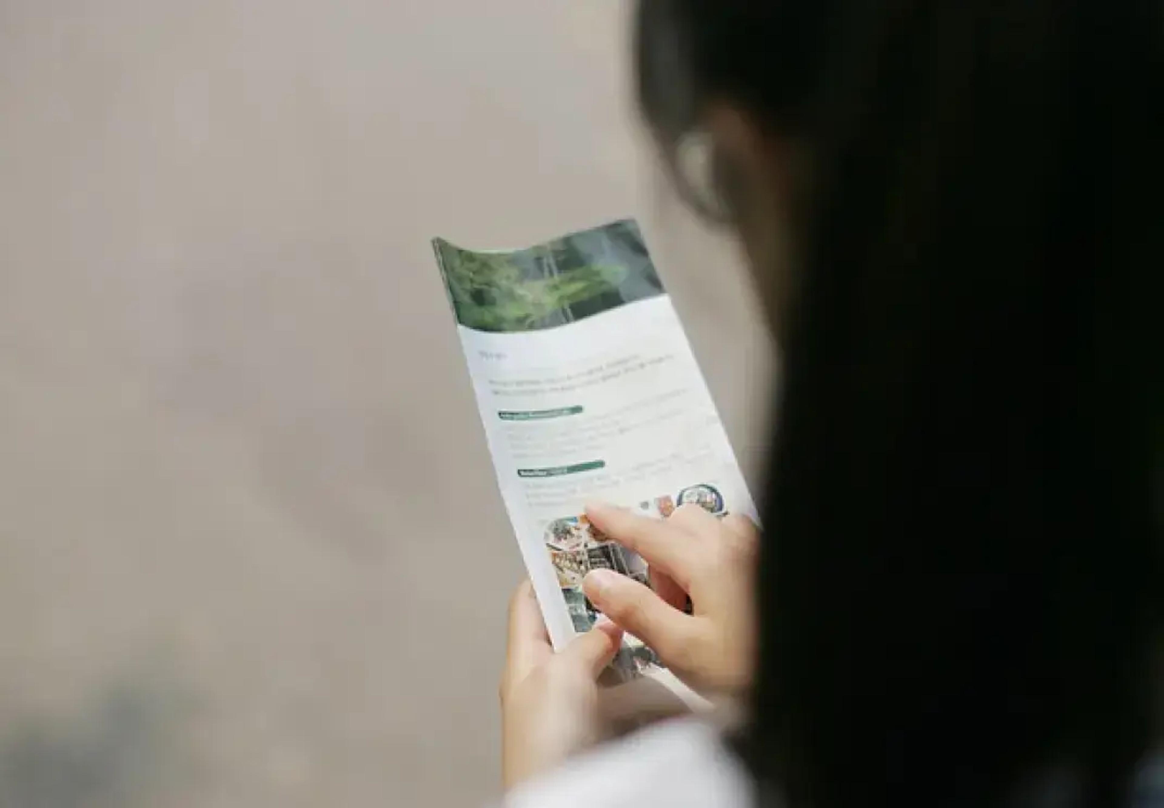 Personne lisant une brochure ou un dépliant avec des images de nature verte