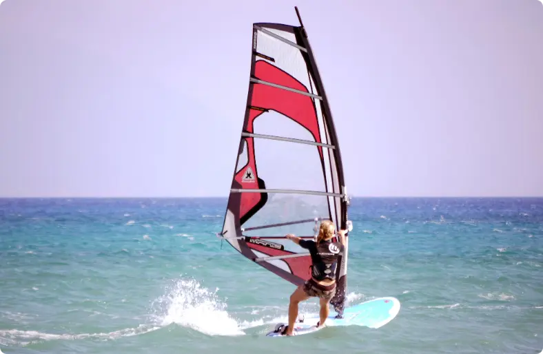 homem andando de prancha de vela sob um céu branco, windsurfing