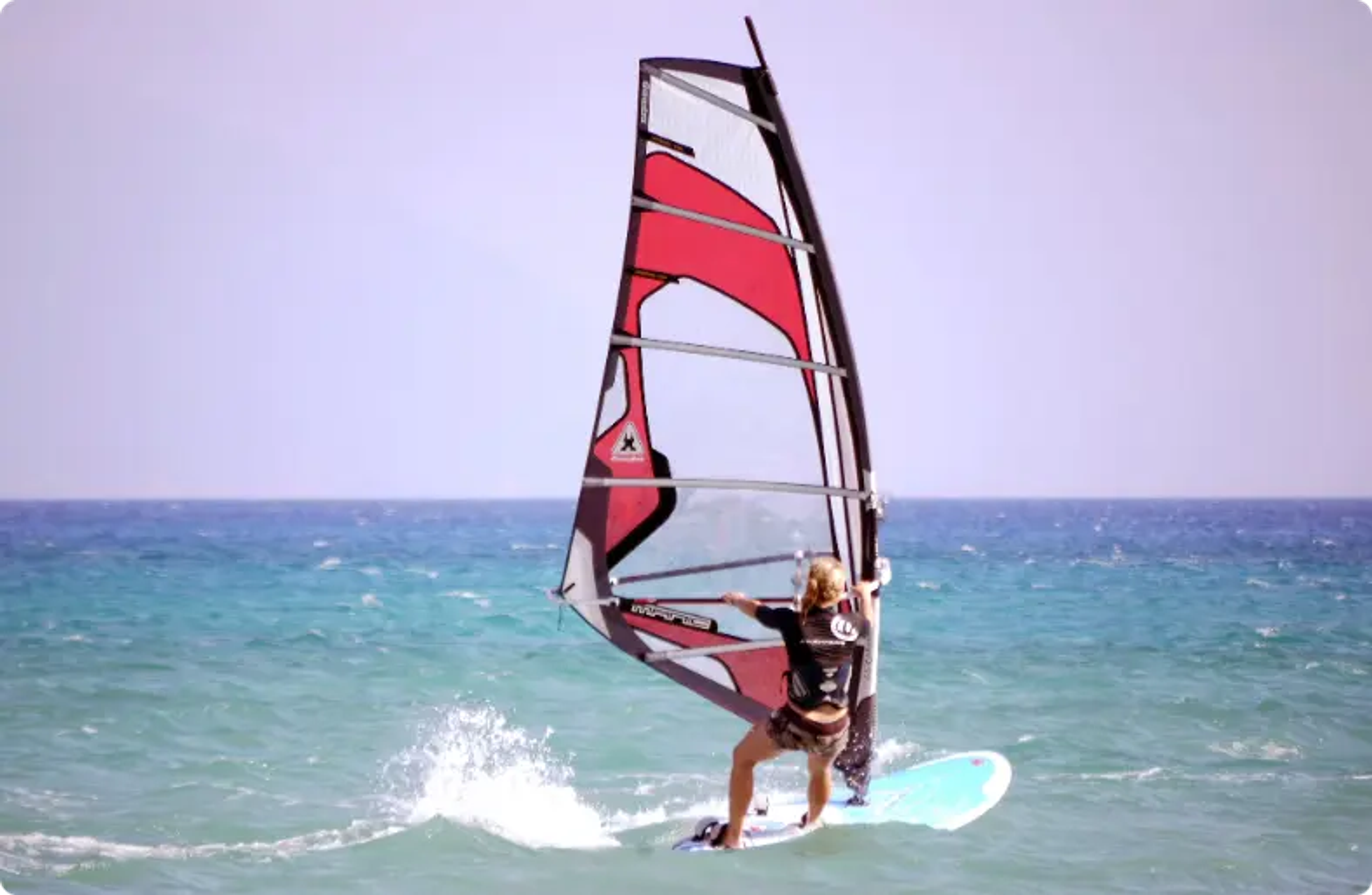 man die op een zeilplank onder een witte lucht surft, windsurfen