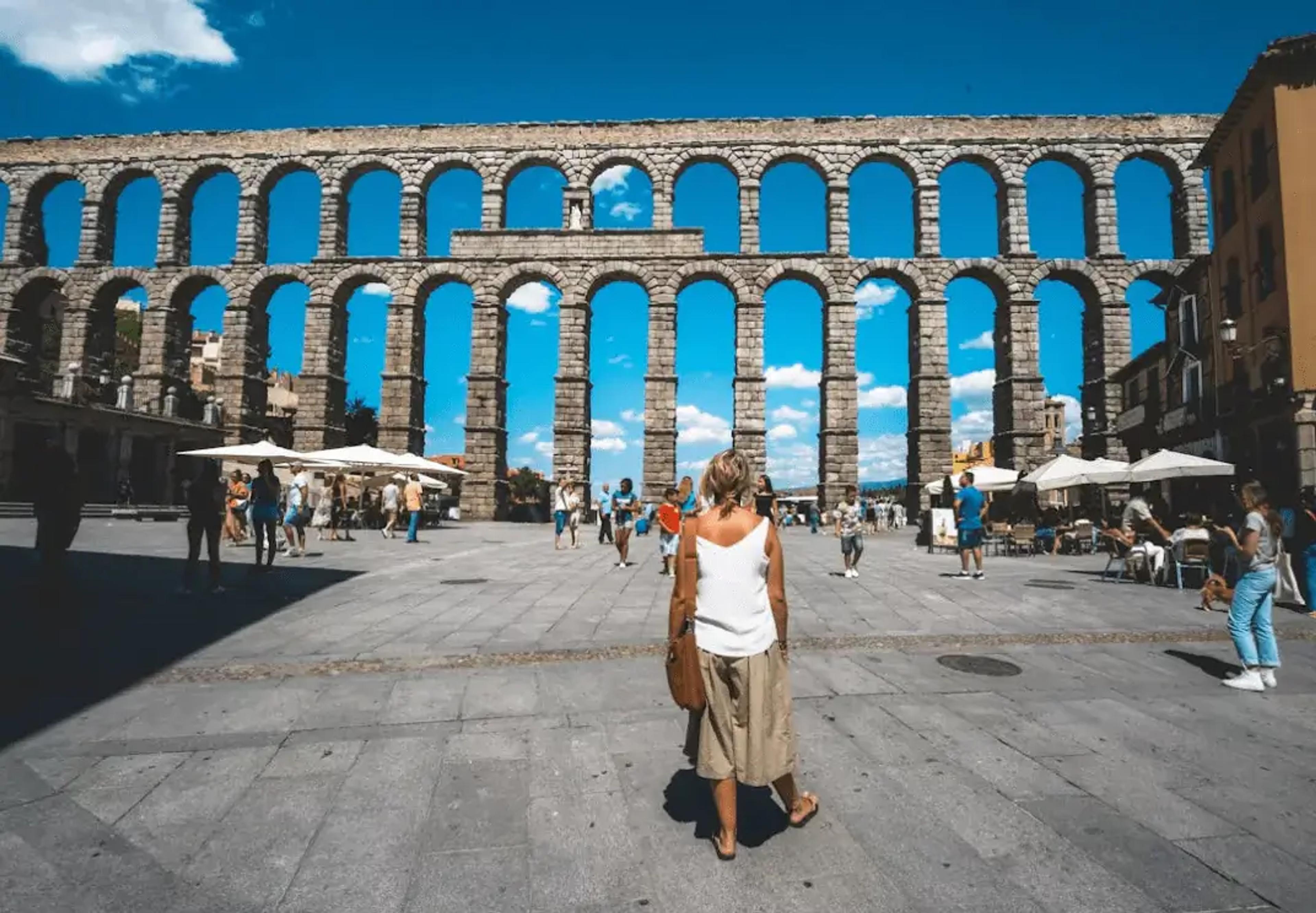 Antik romersk akvædukt i Segovia med turister på en solrig dag