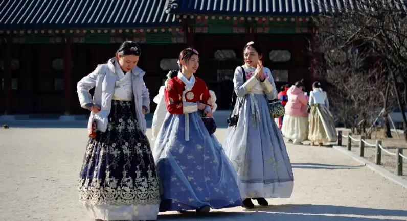 Drie vrouwen in traditionele Koreaanse hanbok-jurken op historische paleisgronden
