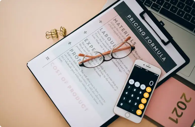 Espacio de trabajo con documento de fórmula de precios, calculadora, gafas y portátil