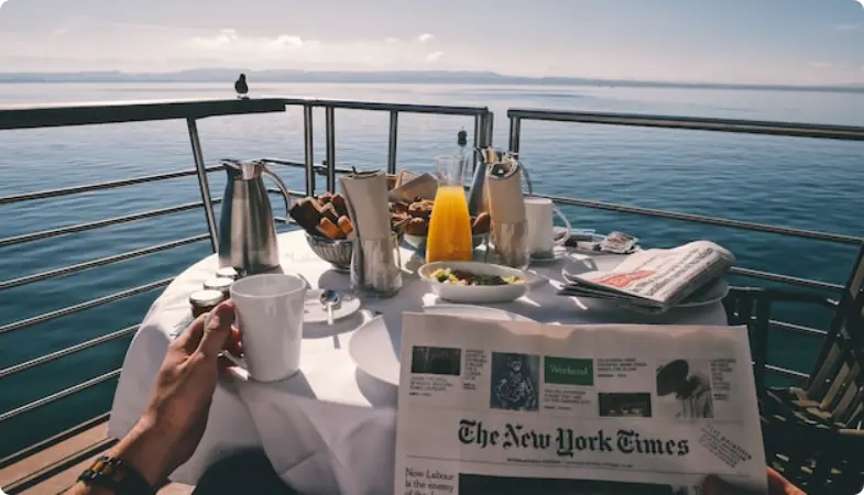 ニューヨーク・タイムズの新聞と海の景色を眺めながらボートデッキでの朝食