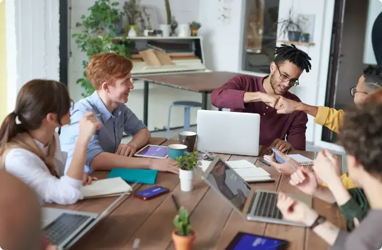 Équipe diversifiée collaborant dans un bureau moderne avec des ordinateurs portables et des plantes