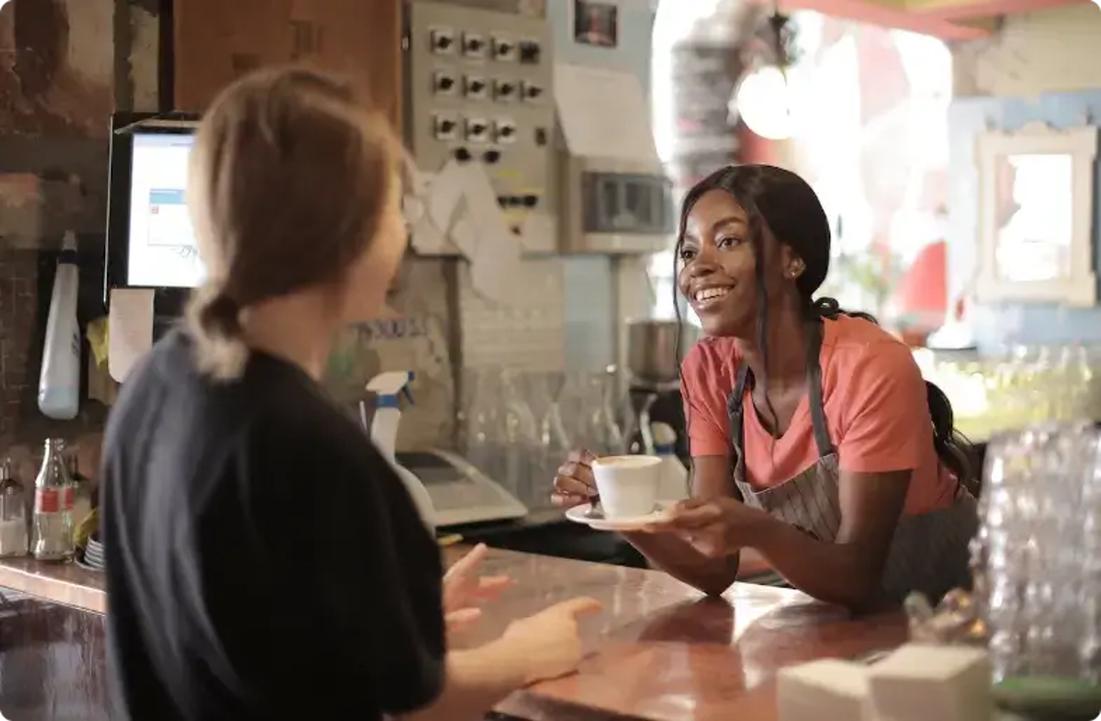 Barista sonriente sirviendo café a un cliente en el mostrador de la cafetería