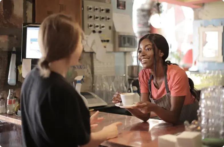 Barista sonriente sirviendo café a un cliente en el mostrador de la cafetería