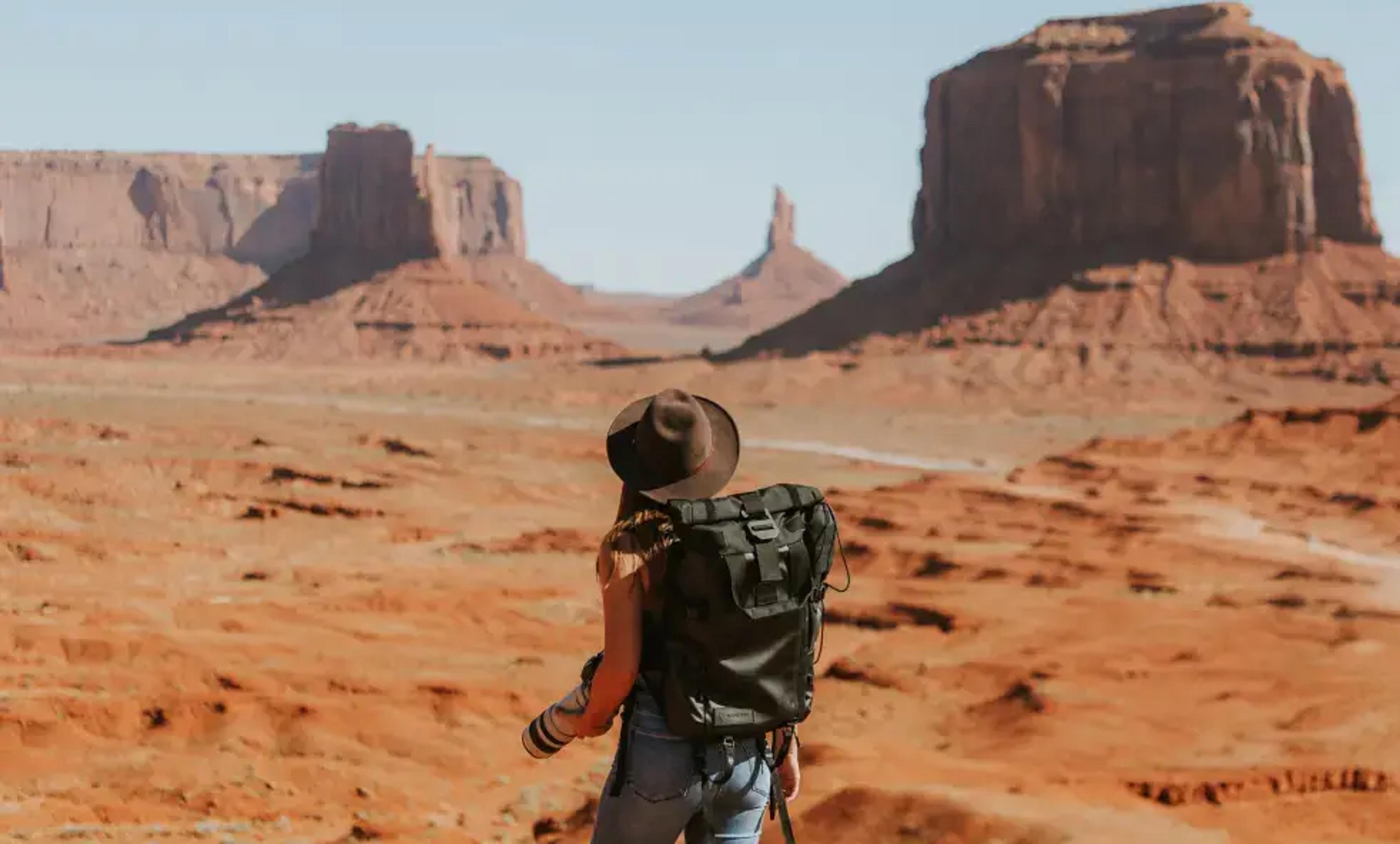 Vandrer med rygsæk med udsigt over ikoniske Monument Valley klippeformationer
