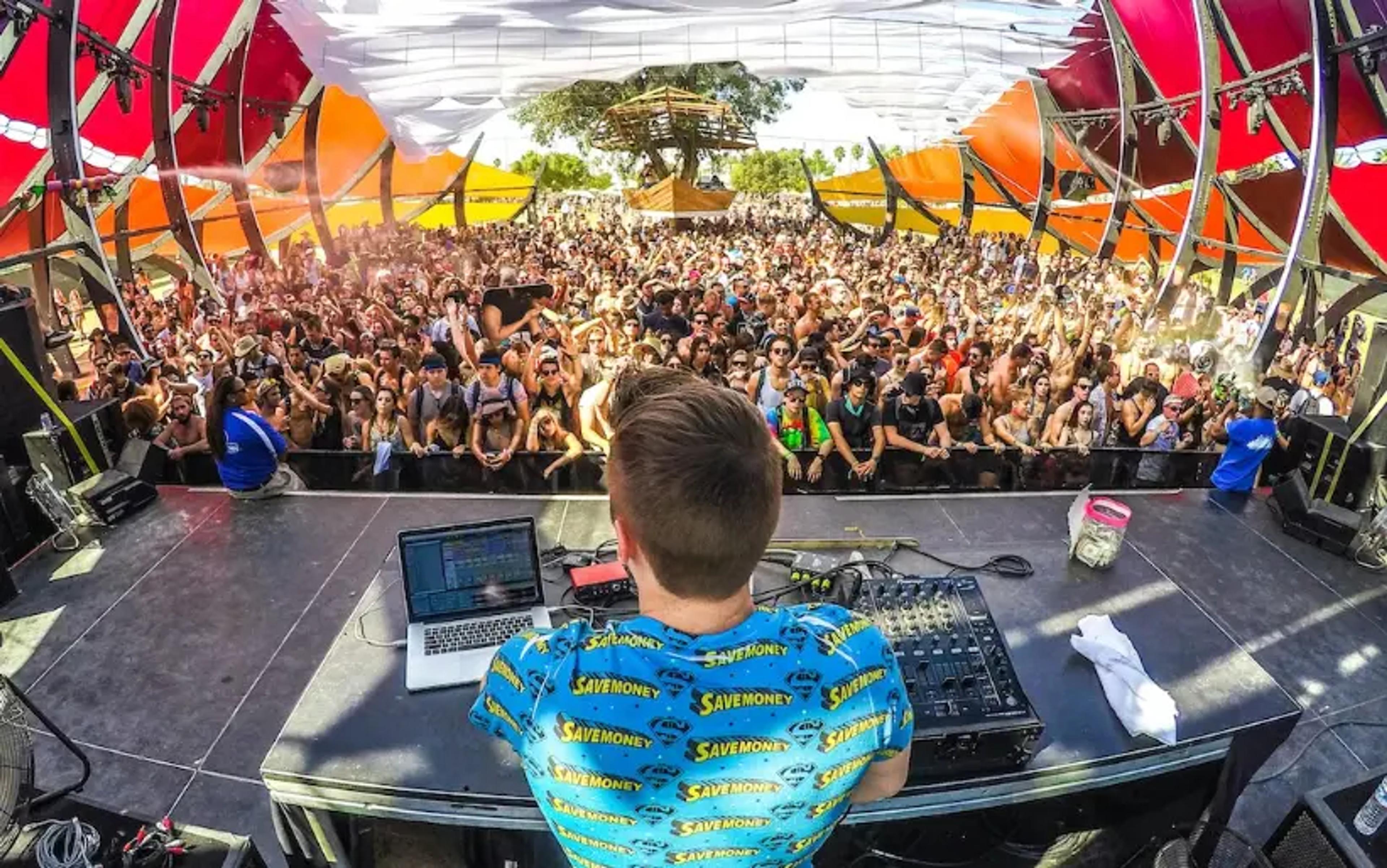 DJ, der auf einem überfüllten Freiluftmusikfestival mit buntem Bühnenhintergrund auftritt