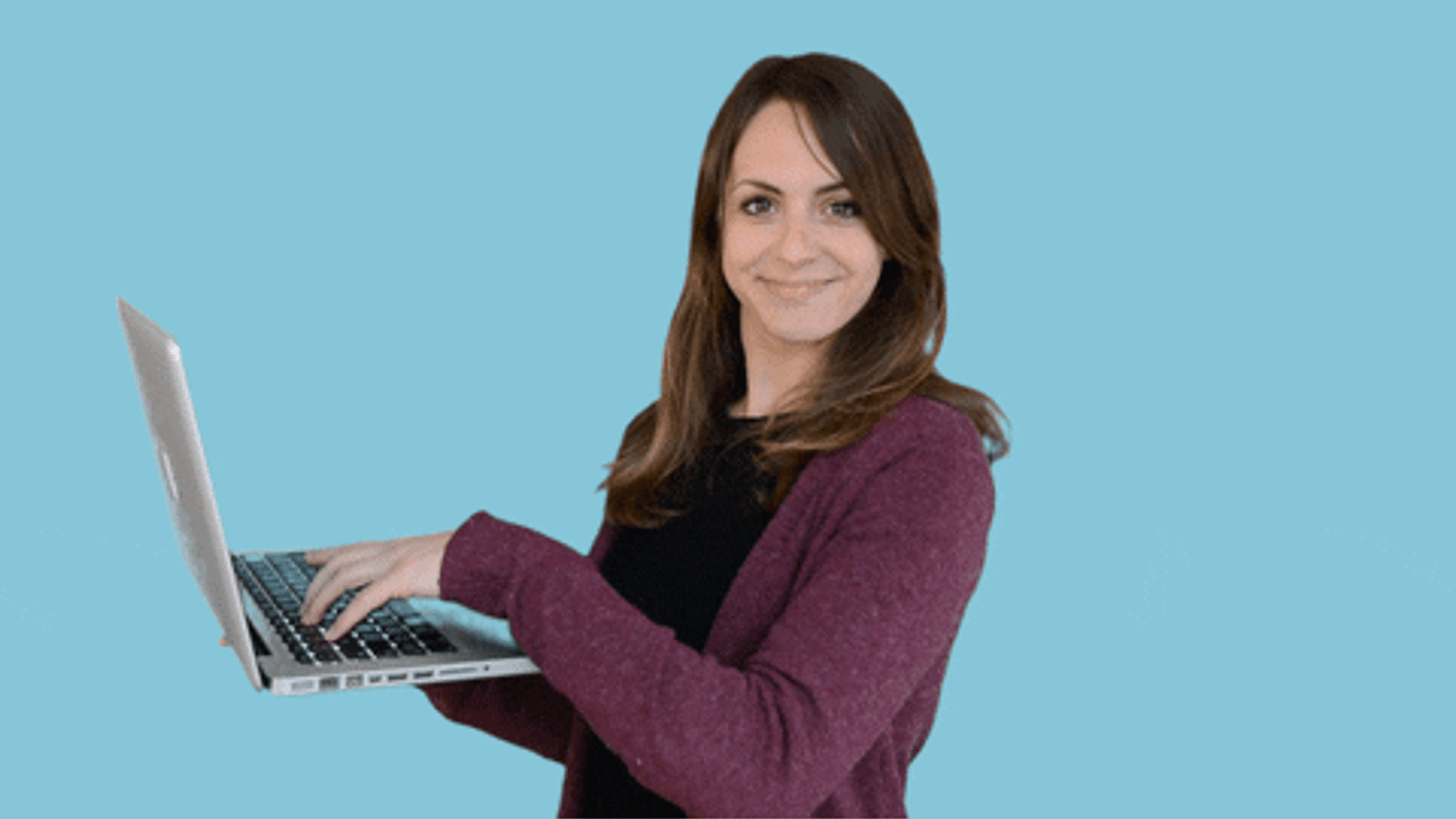 Woman in burgundy sweater smiling and working on laptop against blue background
