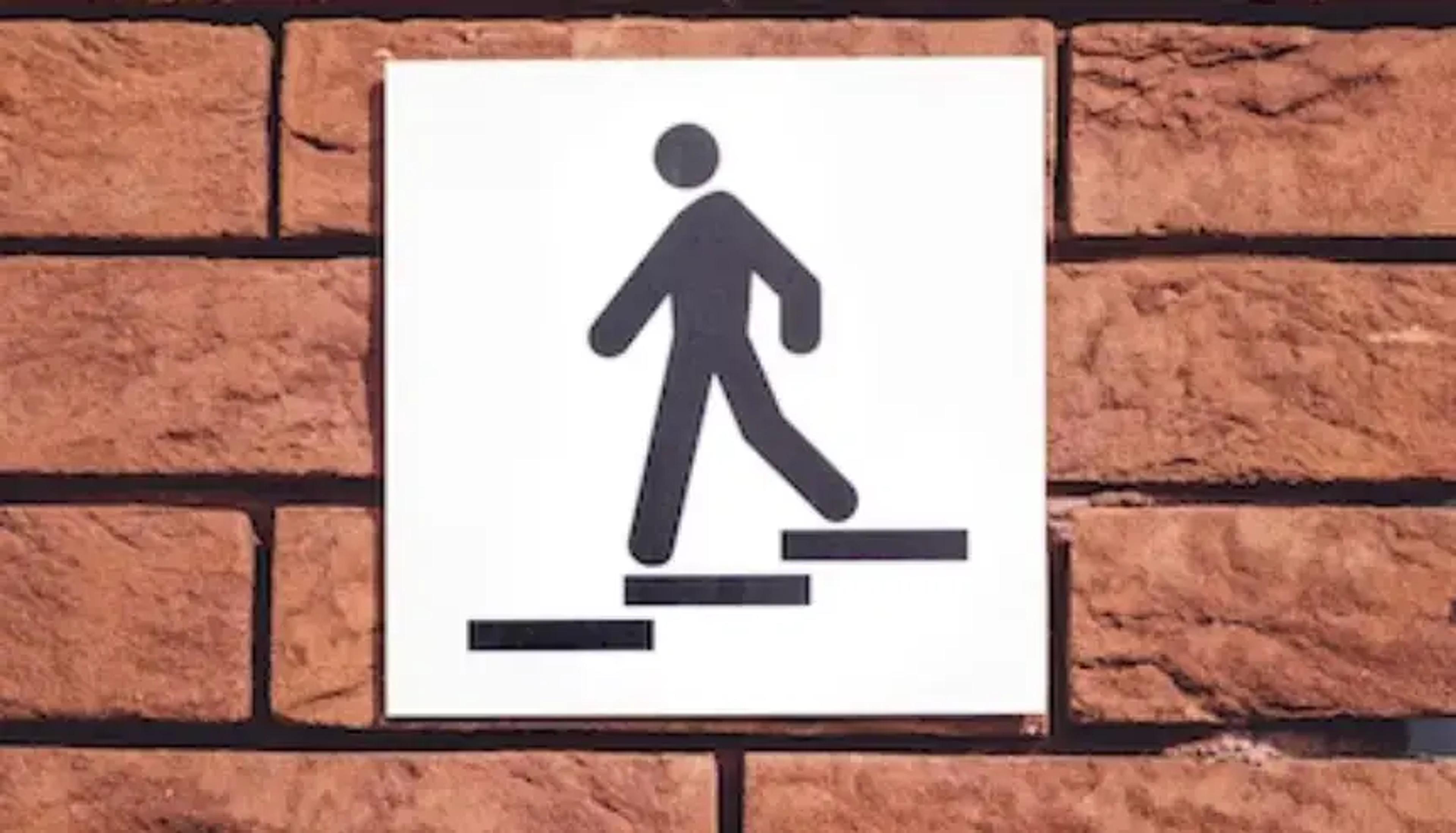 Vejskilt der viser en person, der går op ad en trappe