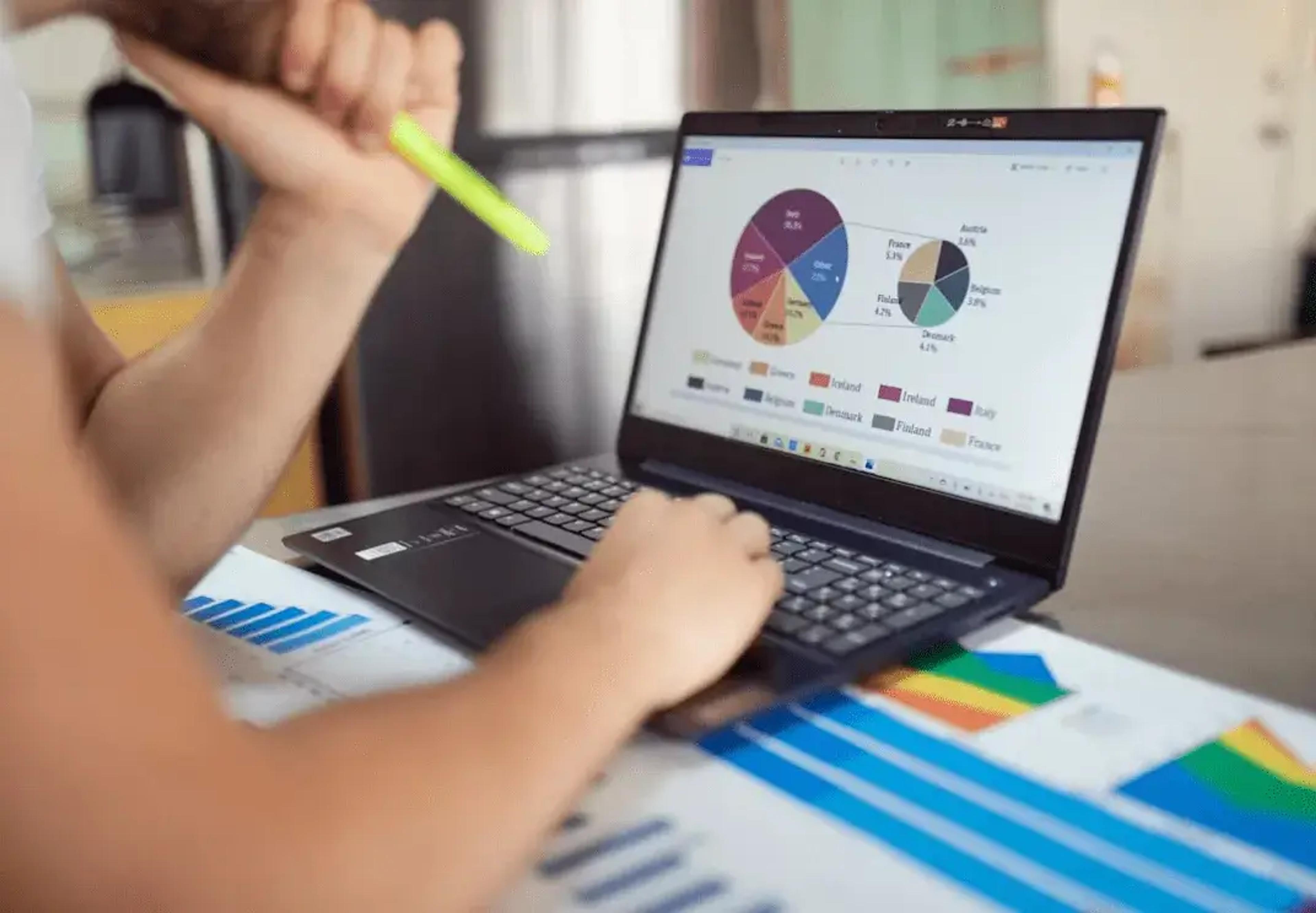 Personne analysant des graphiques circulaires et des graphiques sur un ordinateur portable avec une visualisation de données colorée