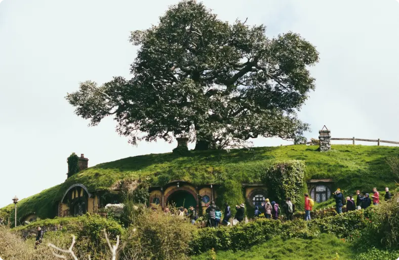 Hobbiton : trou de Hobbit avec un grand arbre sur une colline verte sur le plateau de tournage