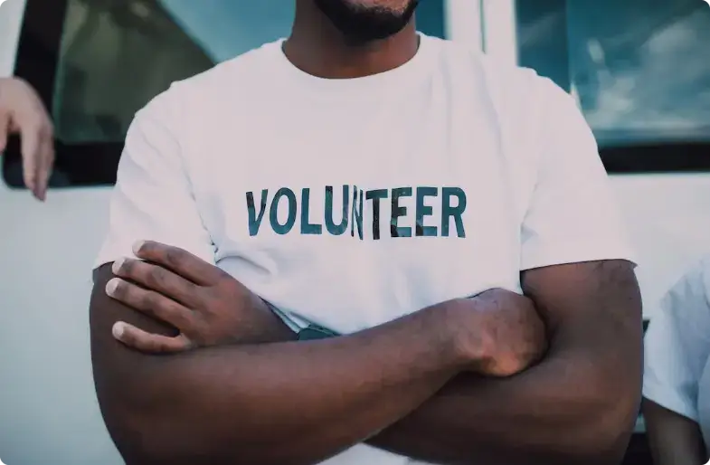 志愿者双臂交叉,穿着印有“Volunteer”字样的白色T恤