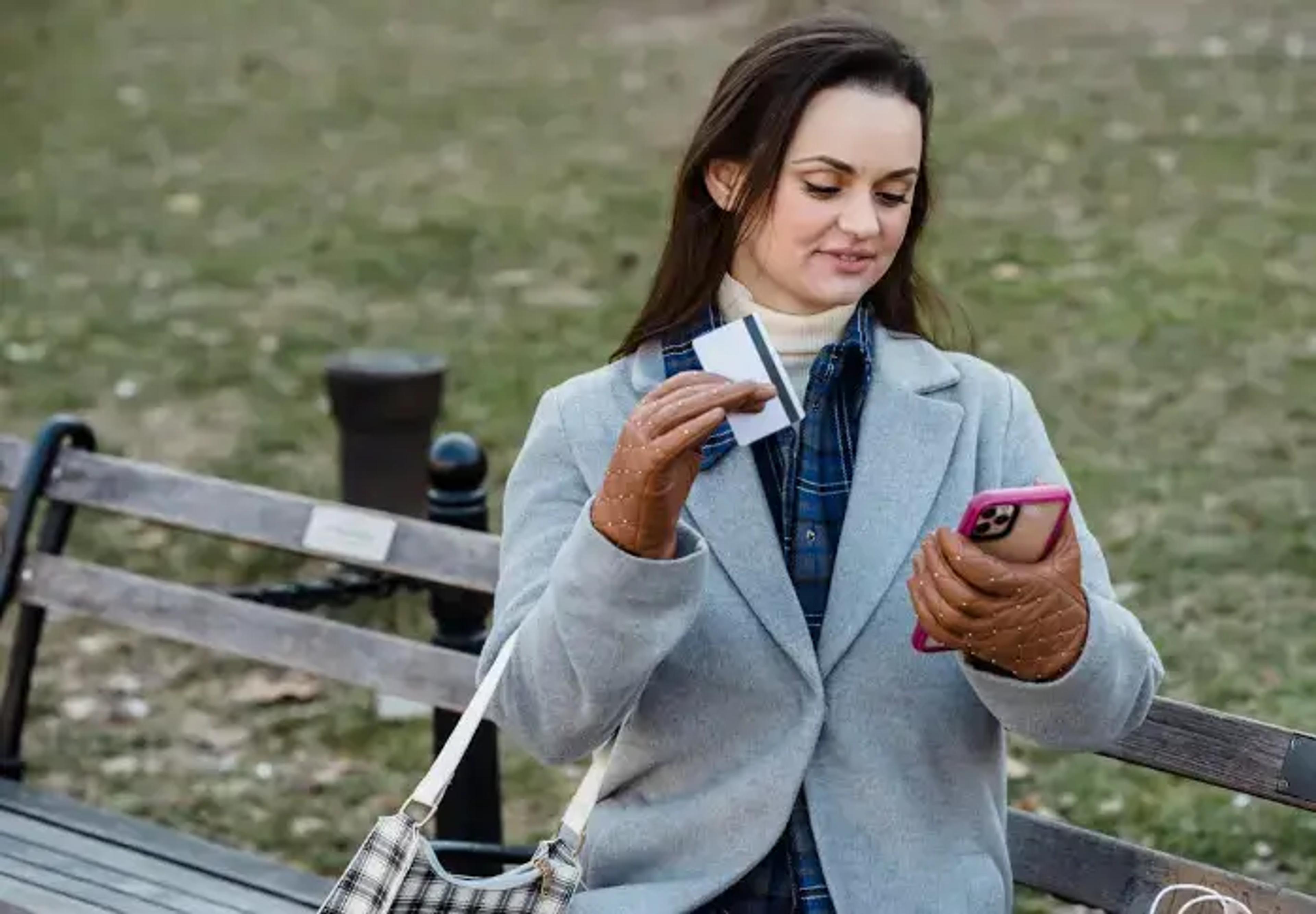 en kvinde, der booker sin rejse online med sin mobiltelefon og betalingskort