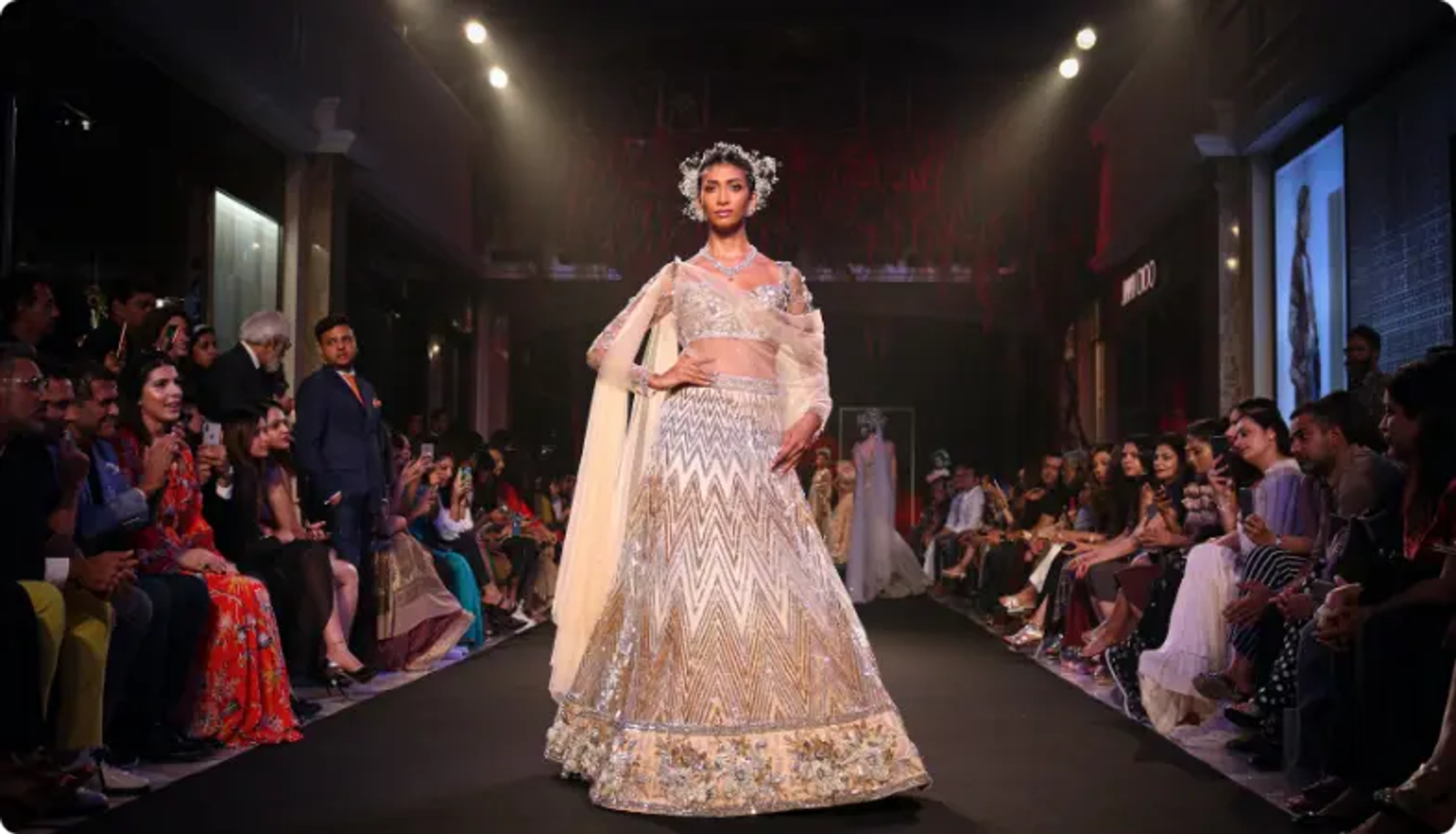 Model in elegant white and gold wedding lehenga walking runway at fashion show