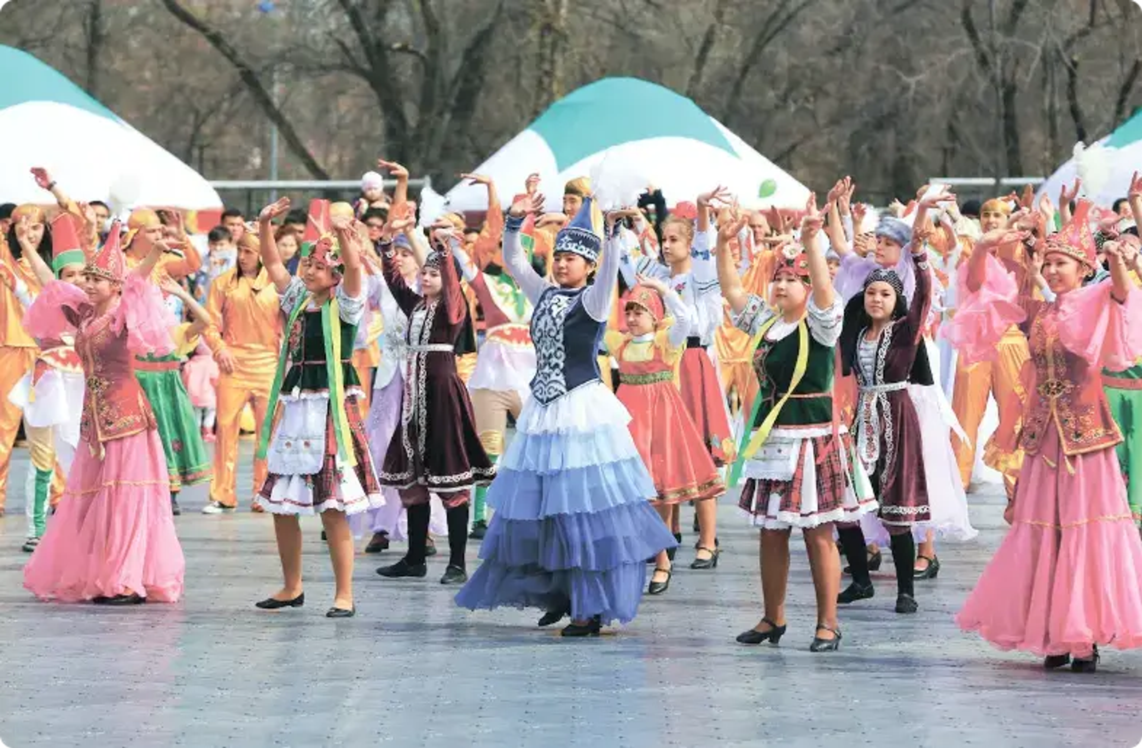 Farverige traditionelle dansere optræder sammen med hævede arme udendørs