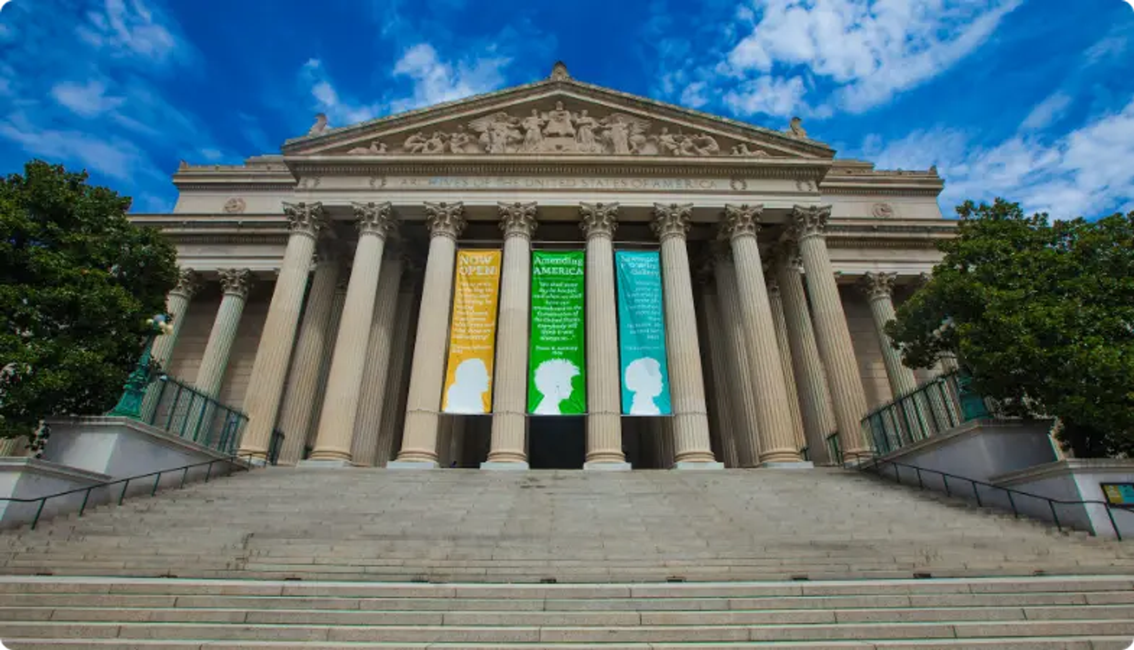 Edifício neoclássico com banners coloridos contra o céu azul e árvores verdes