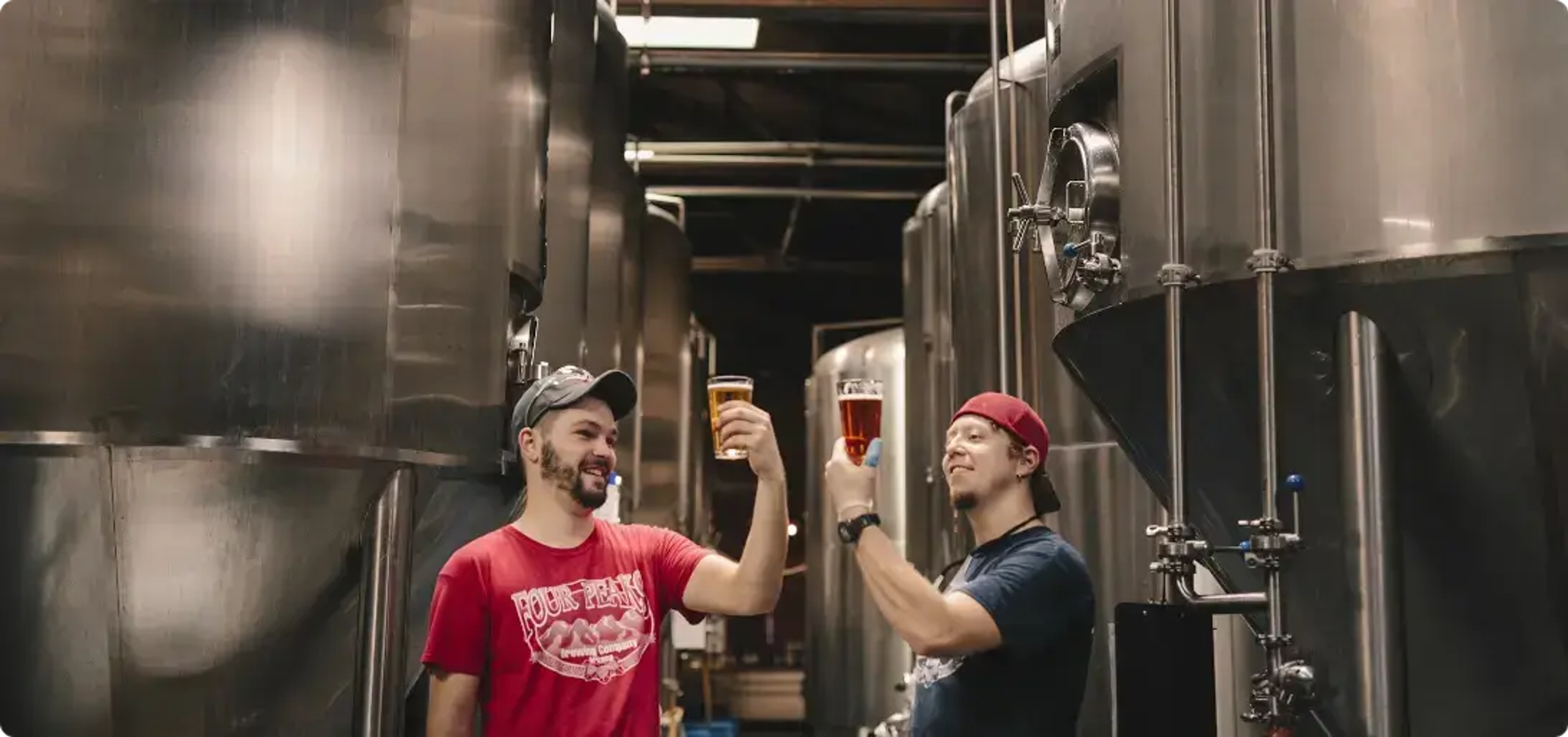 dos hombres en operaciones de cervecería sosteniendo sus vasos y sonriendo