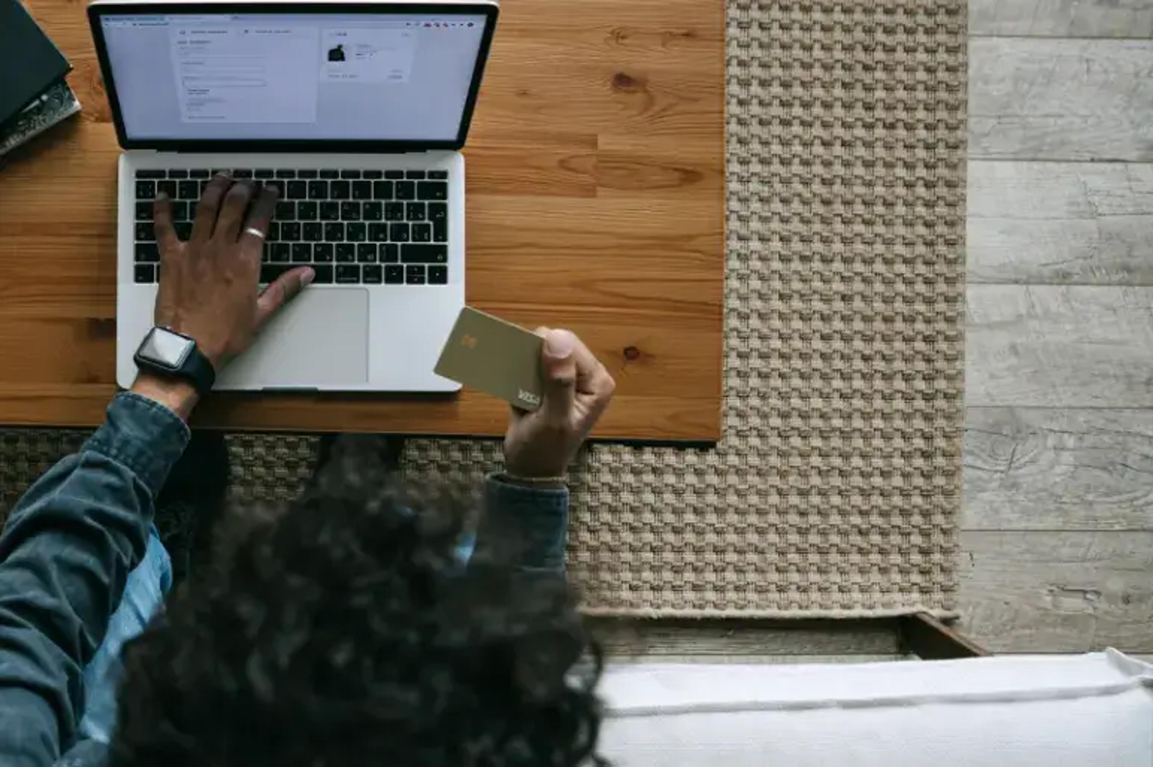 Persoon die laptop gebruikt en creditcard vasthoudt voor online winkelen