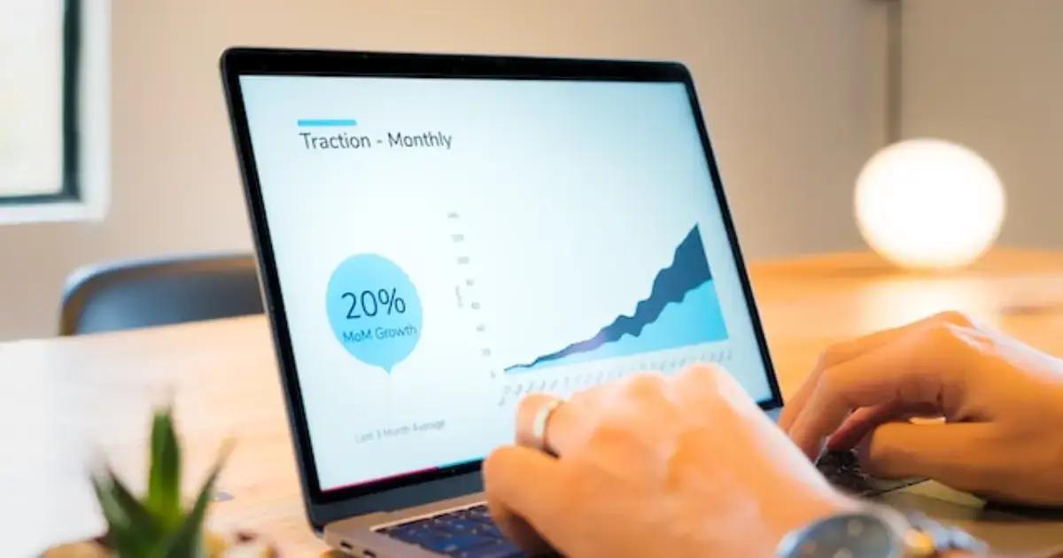 Laptop screen showing monthly traction graph with 20% growth
