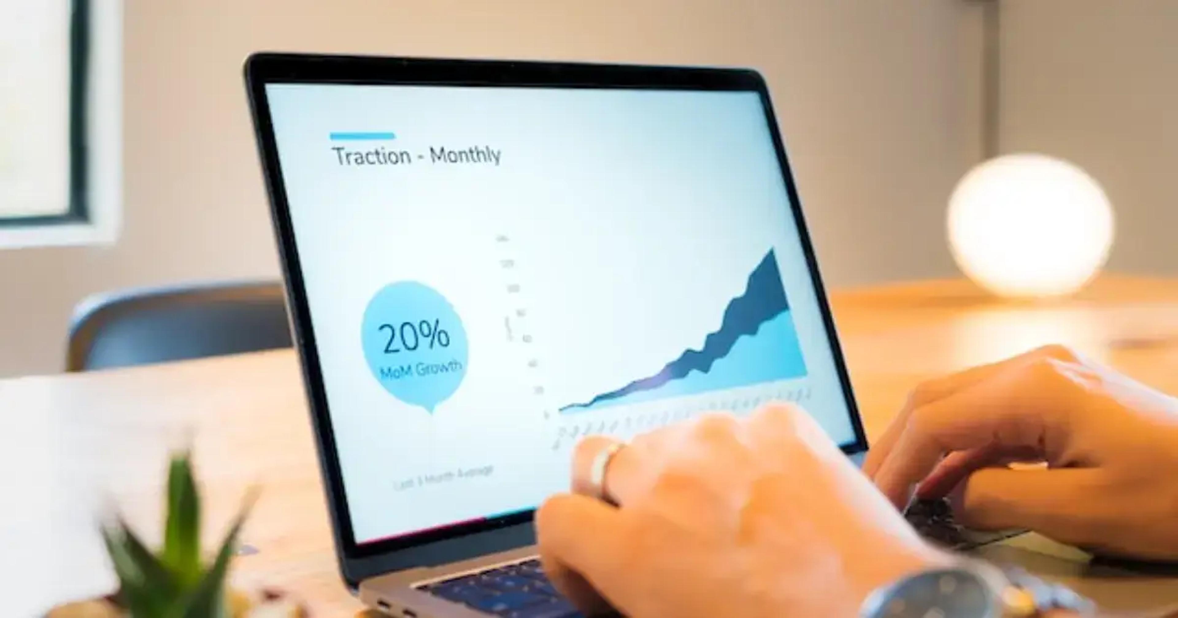Pantalla de laptop mostrando gráfico de tracción mensual con un crecimiento del 20%