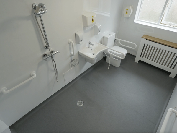 A level-access wet room with grab rails and a glass screen