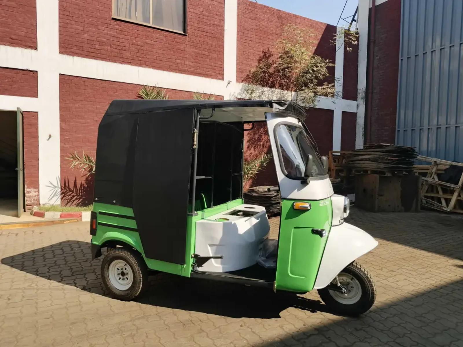 Side view of a green and white Sazgar electric rickshaw