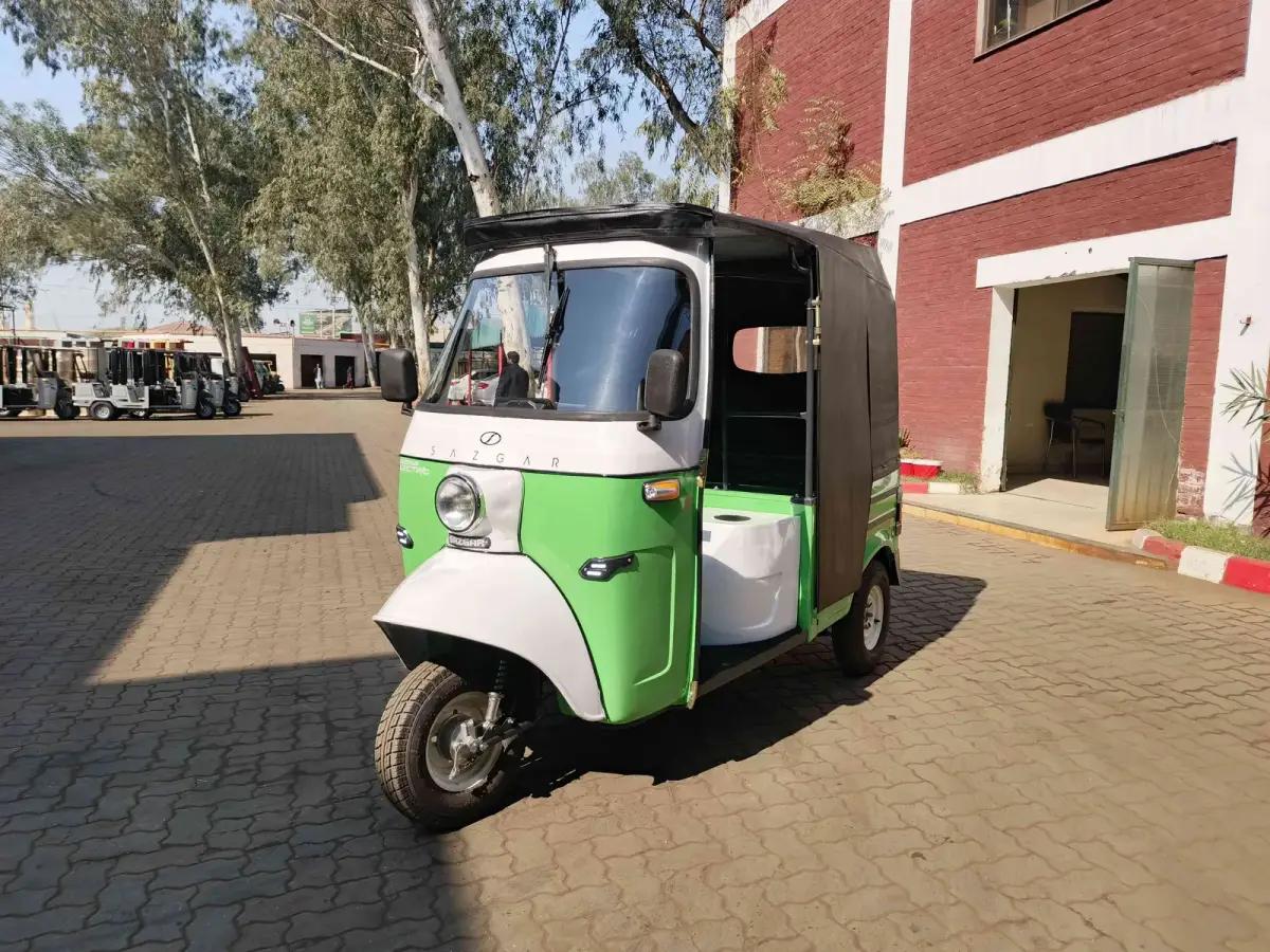 Green and white Sazgar electric rickshaw in a factory courtyard