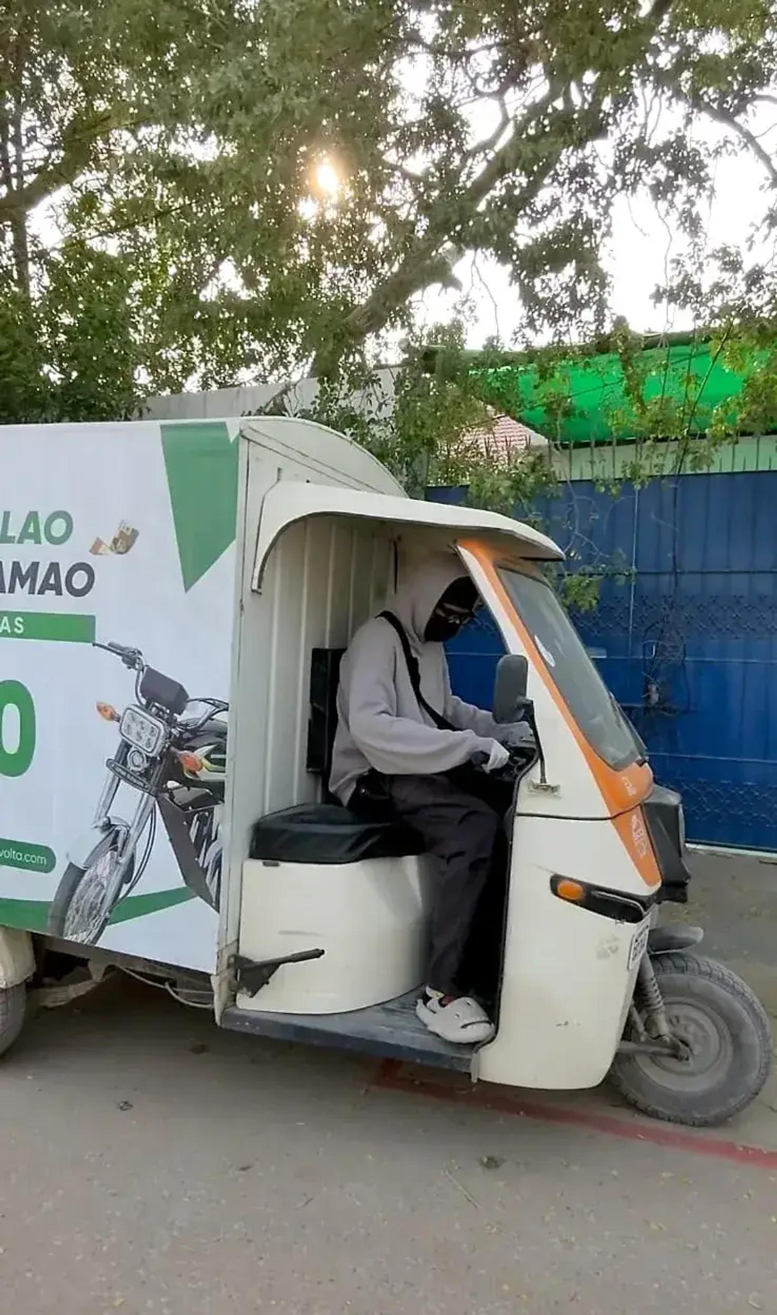 Rider in an electric loader rickshaw with a Zvolta advertising panel