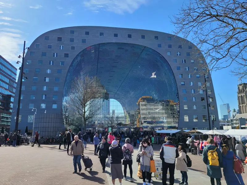 Feestvierders in oranje kleding tijdens Koningsdag in Rotterdam met skyline op de achtergrond