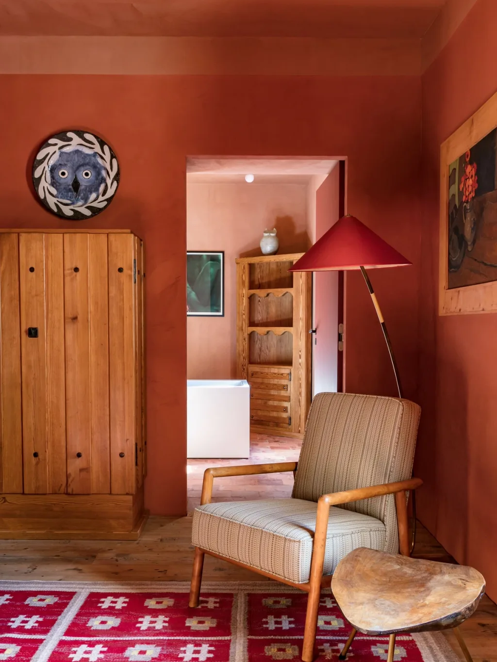 Striped armchair and red floor lamp in a red-walled room at Fabrègues, Pierre Yovanovitch