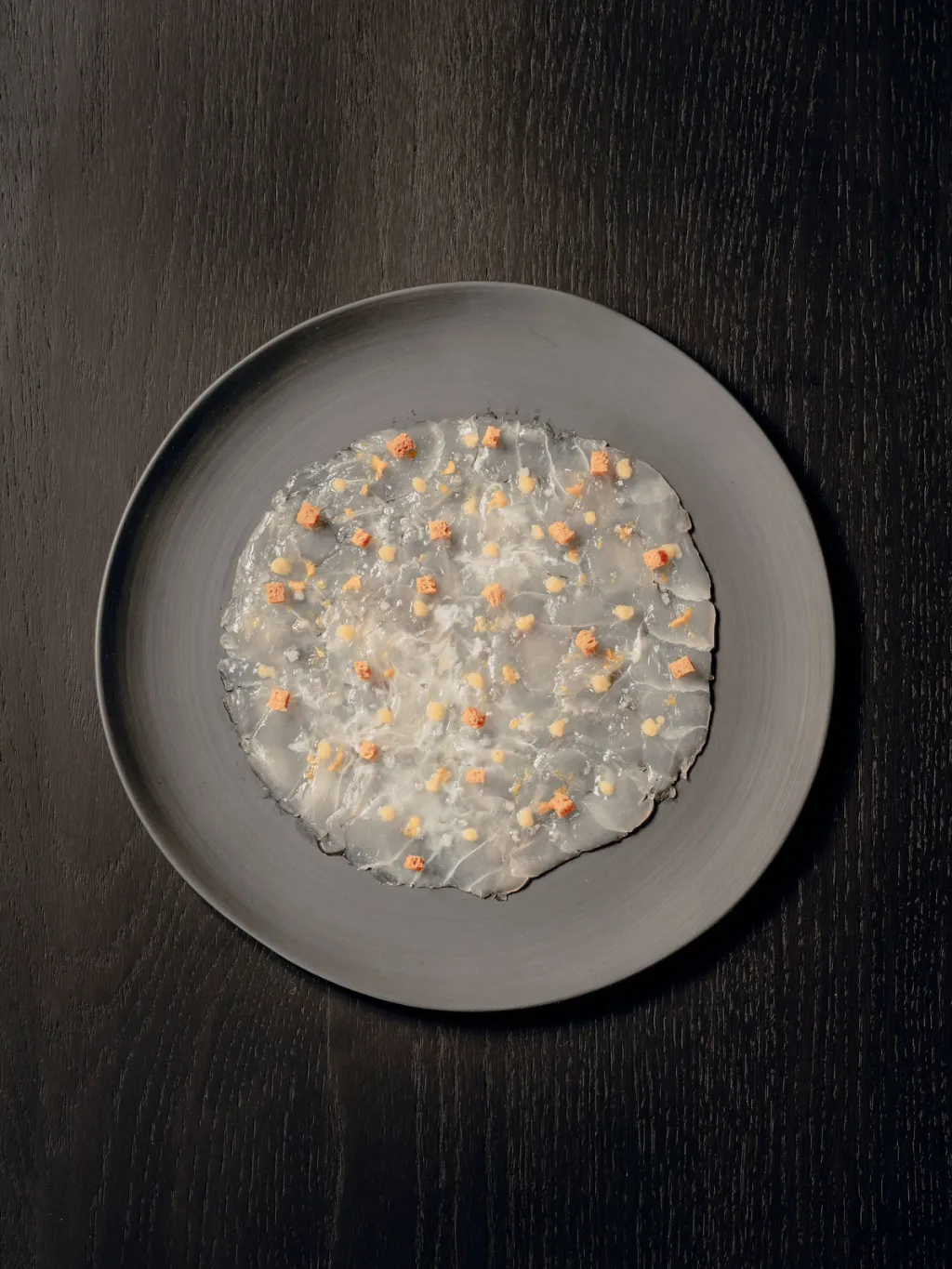 Translucent slices arranged in a circle on a grey plate for Cyril Lignac’s Saisons cookbook