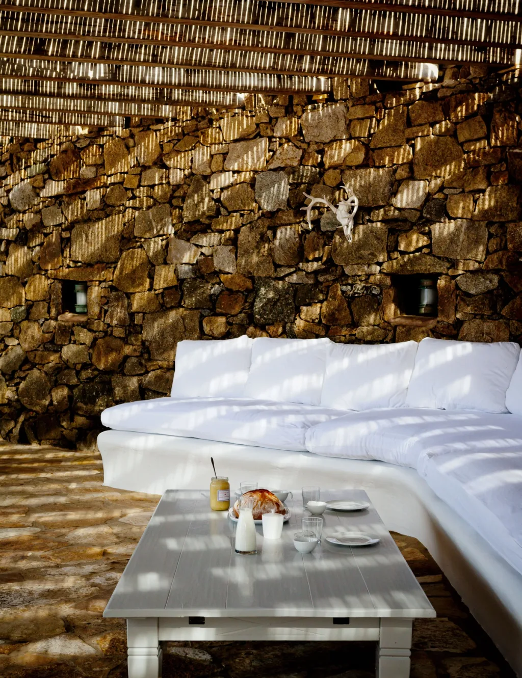 Whitewashed cubist facade with twin chimneys above a pool and the sea, a hotel in Mykonos