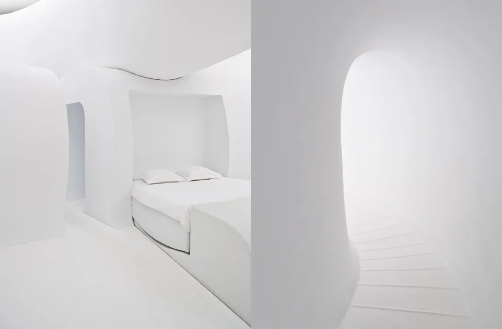 White bed recessed within curved walls beside a rounded passage, The Snake by François Roche