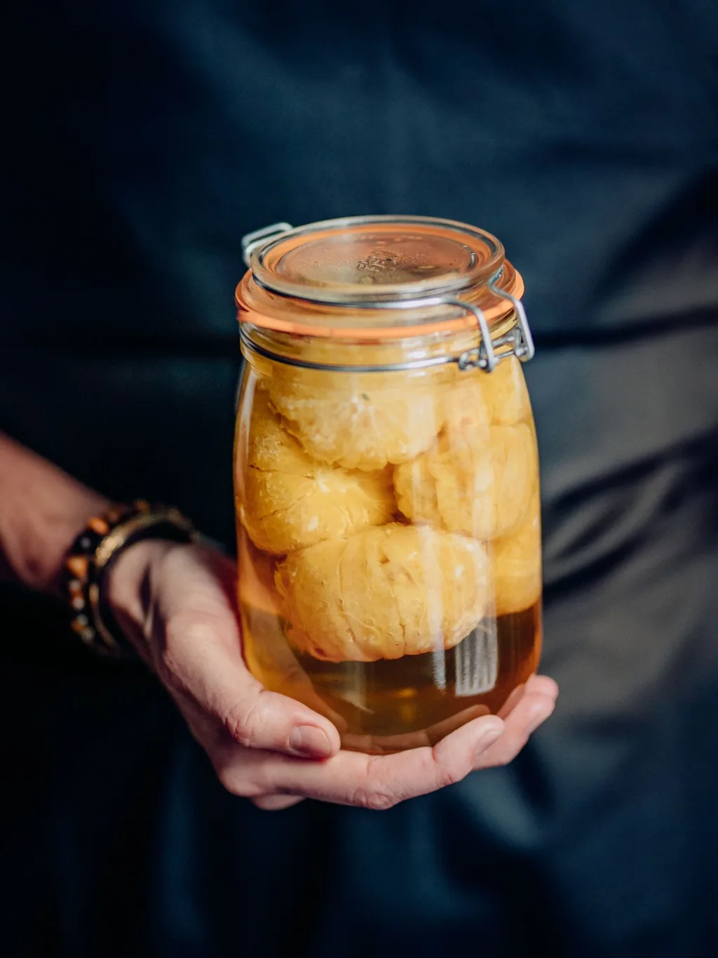Hands holding a jar of peeled citrus in syrup for Cyril Lignac’s Saisons cookbook