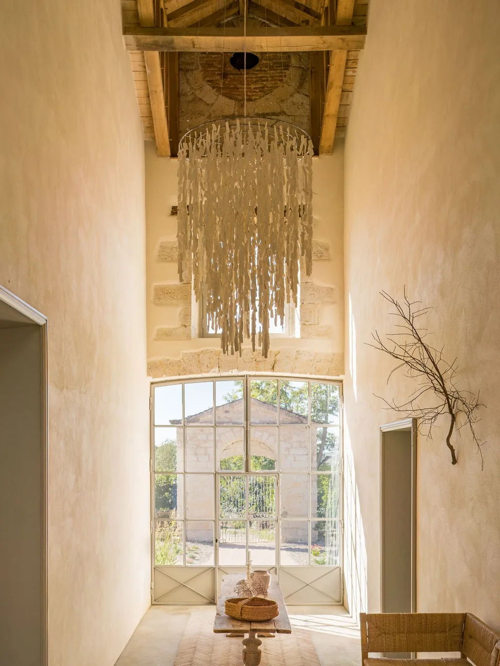 Fringed paper chandelier hangs beneath exposed beams at Manufacture Royale de Lectoure hotel