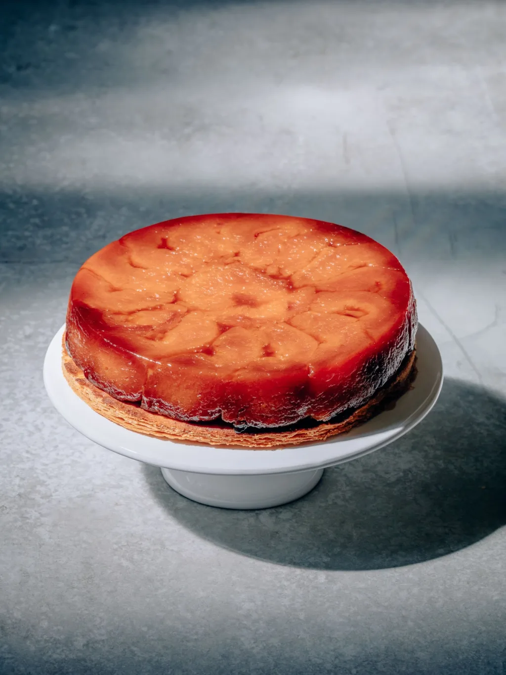 Deep golden fruit tart on a white pedestal cake stand for Cyril Lignac’s Saisons cookbook