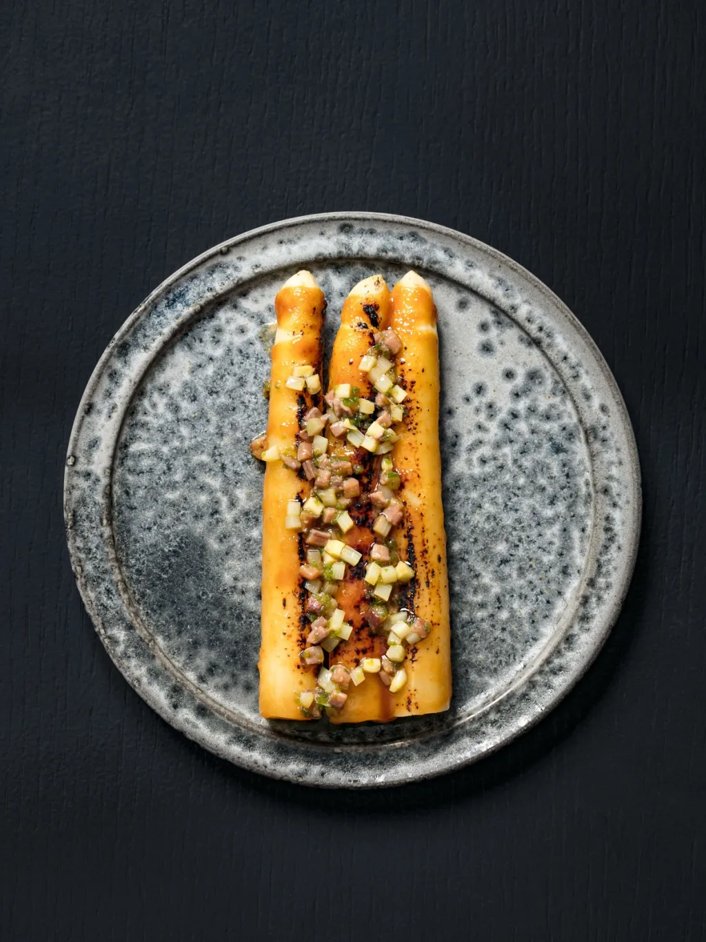 Three golden asparagus spears with a diced topping for Cyril Lignac’s Saisons cookbook