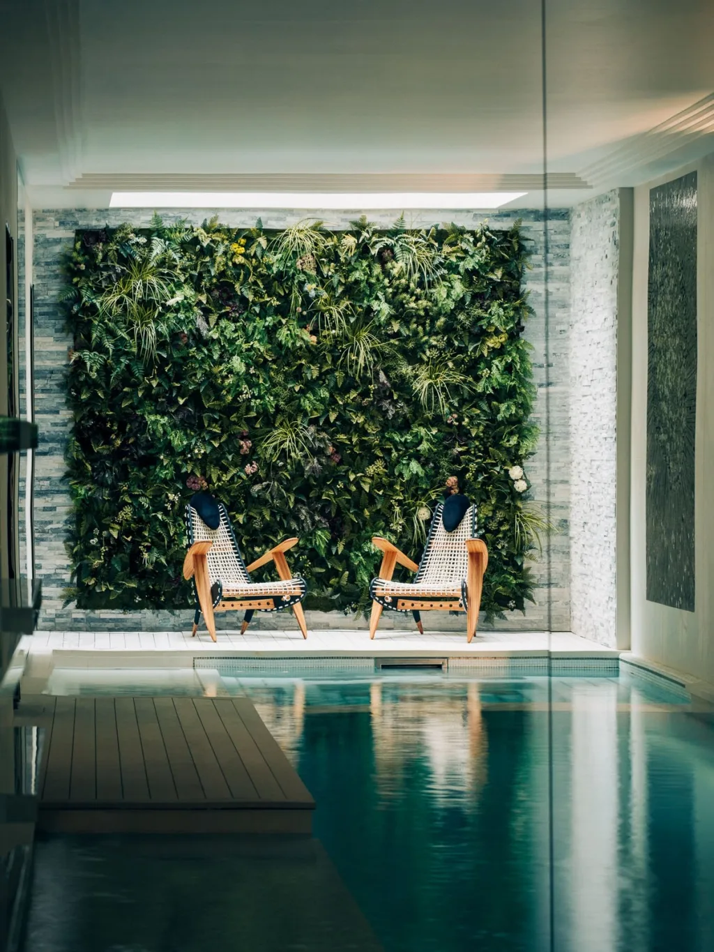Indoor pool facing a planted wall and two lounge chairs in Stéphanie Coutas' Paris interior