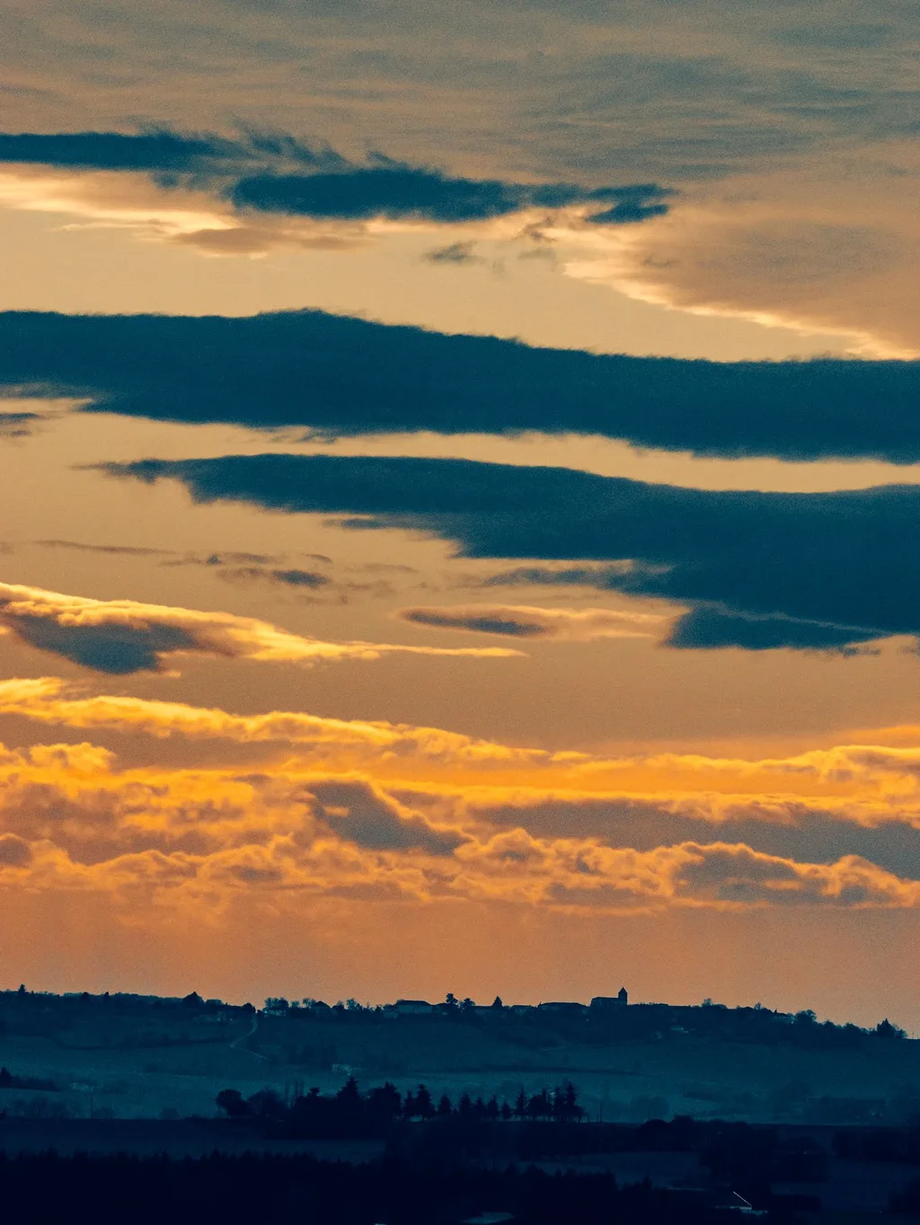 Layered sunset clouds over a hilltop village near Manufacture Royale de Lectoure hotel