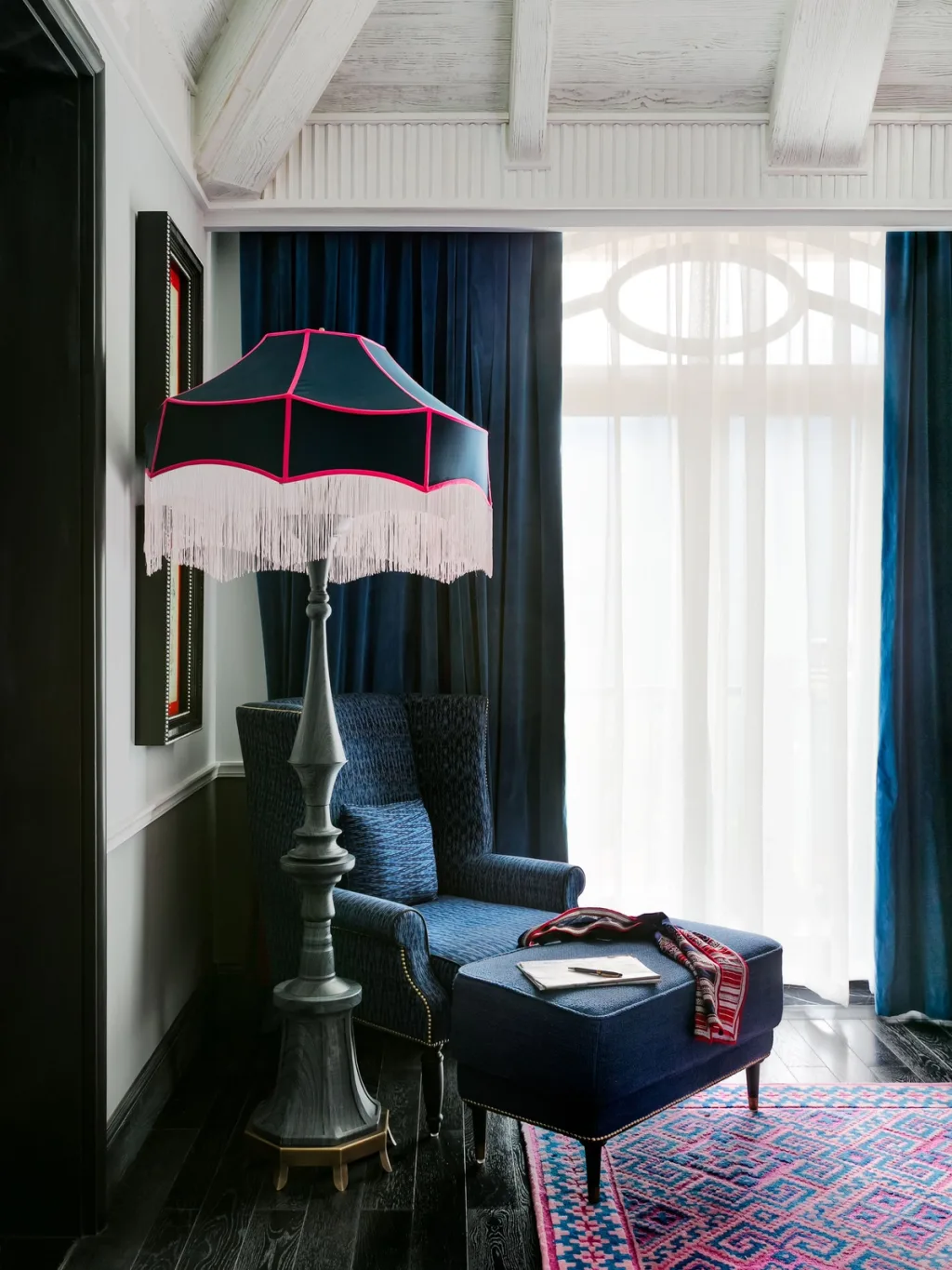 Fringed umbrella floor lamp beside a navy armchair under sloped beams, Hotel de la Coupole MGallery, Sapa, Vietnam