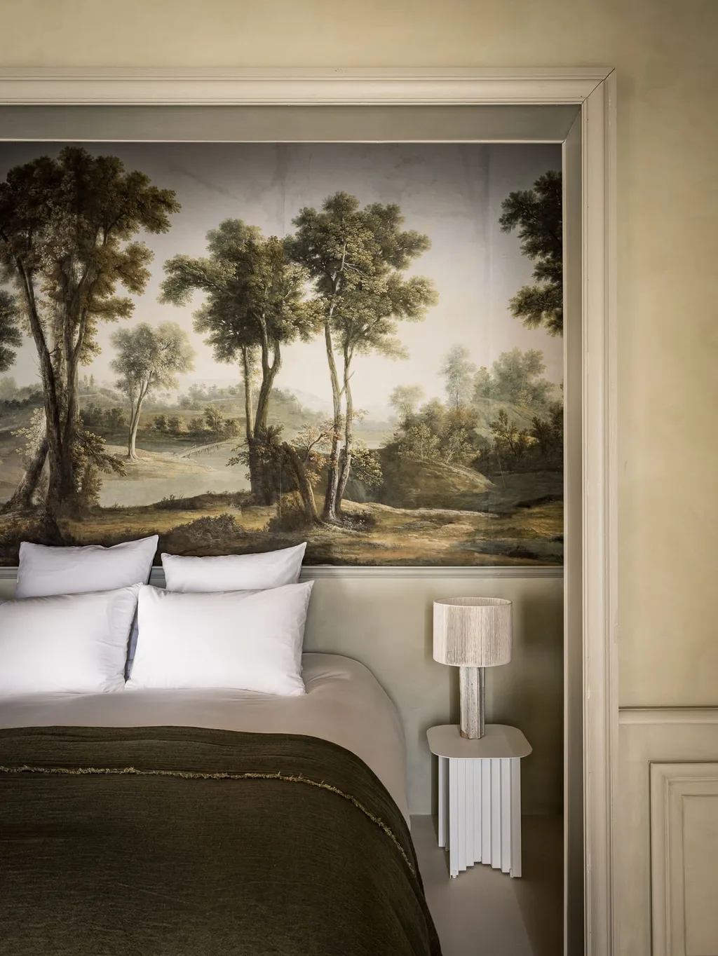Antique forest mural hangs above the bed's white pillows, Manufacture Royale de Lectoure hotel