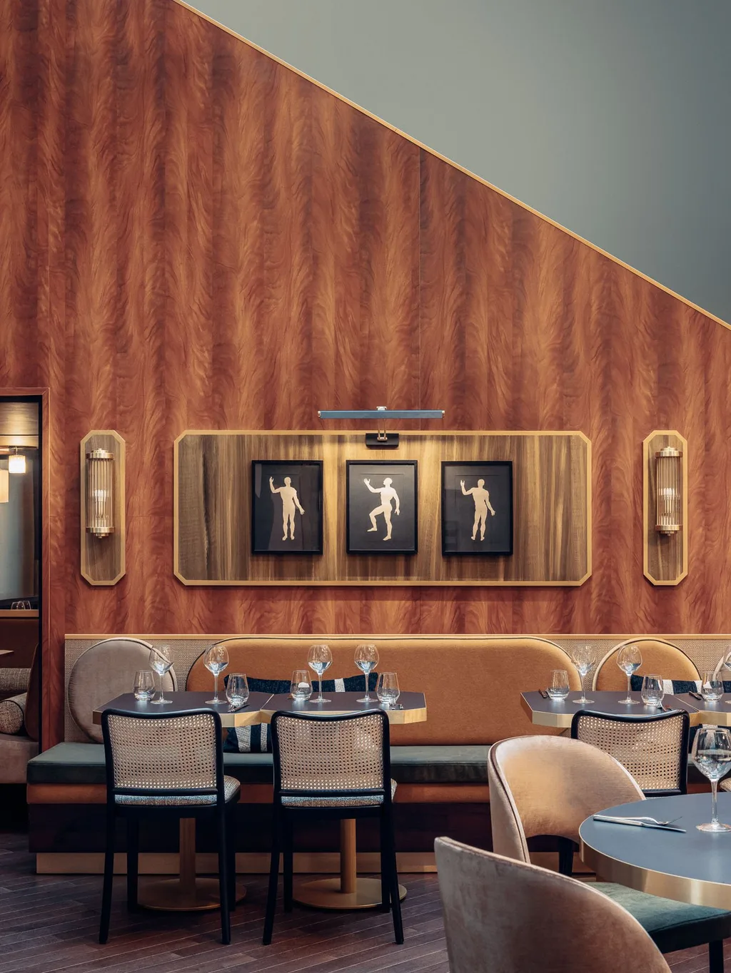 Walnut-paneled dining nook with framed figure prints and cane chairs, Nest MGallery Hotel, Paris