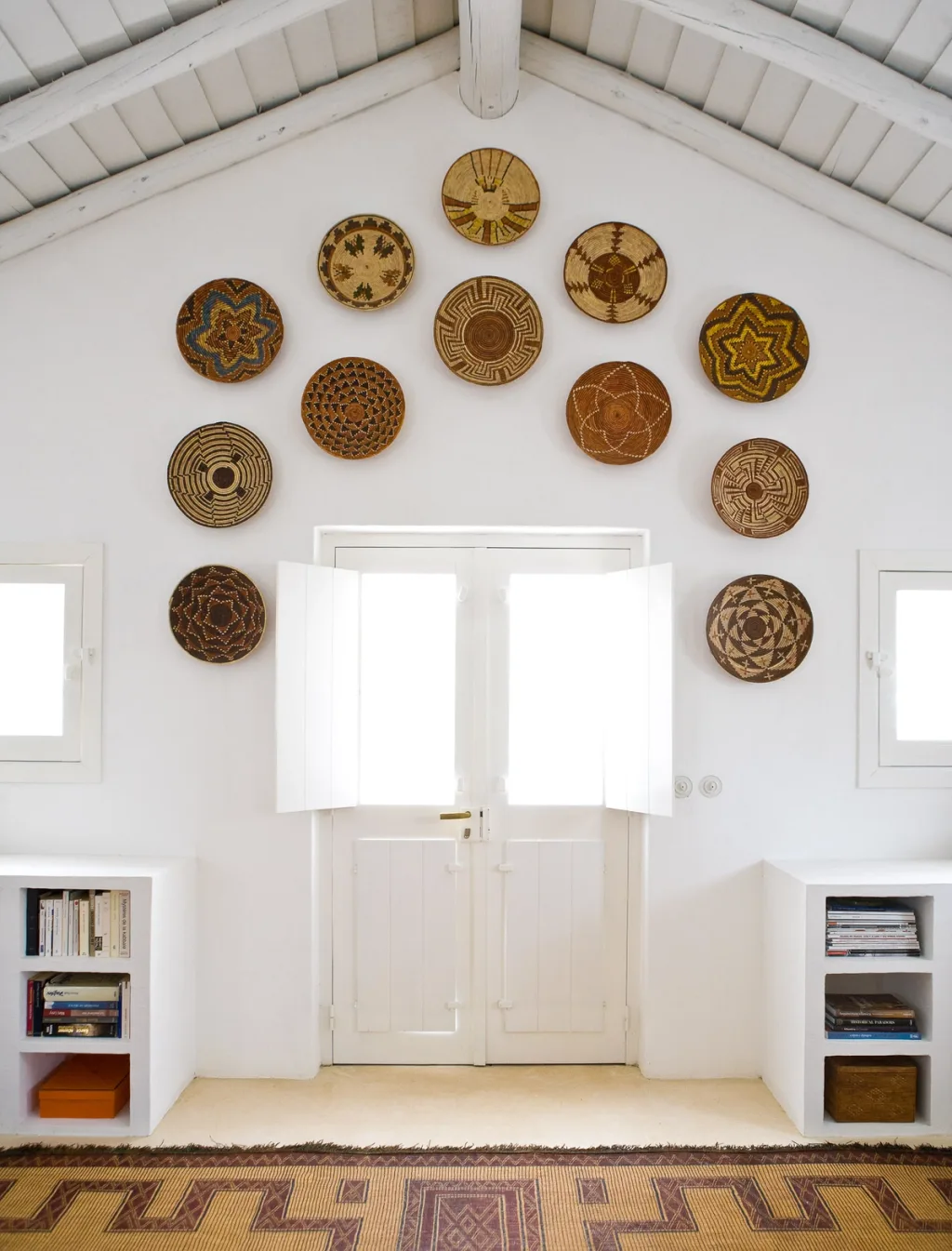 Patterned woven baskets around white double doors beneath rafters, Jacques Grange, Comporta